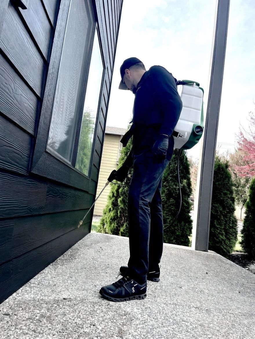 Orb Pest Control technician treating exterior of home 