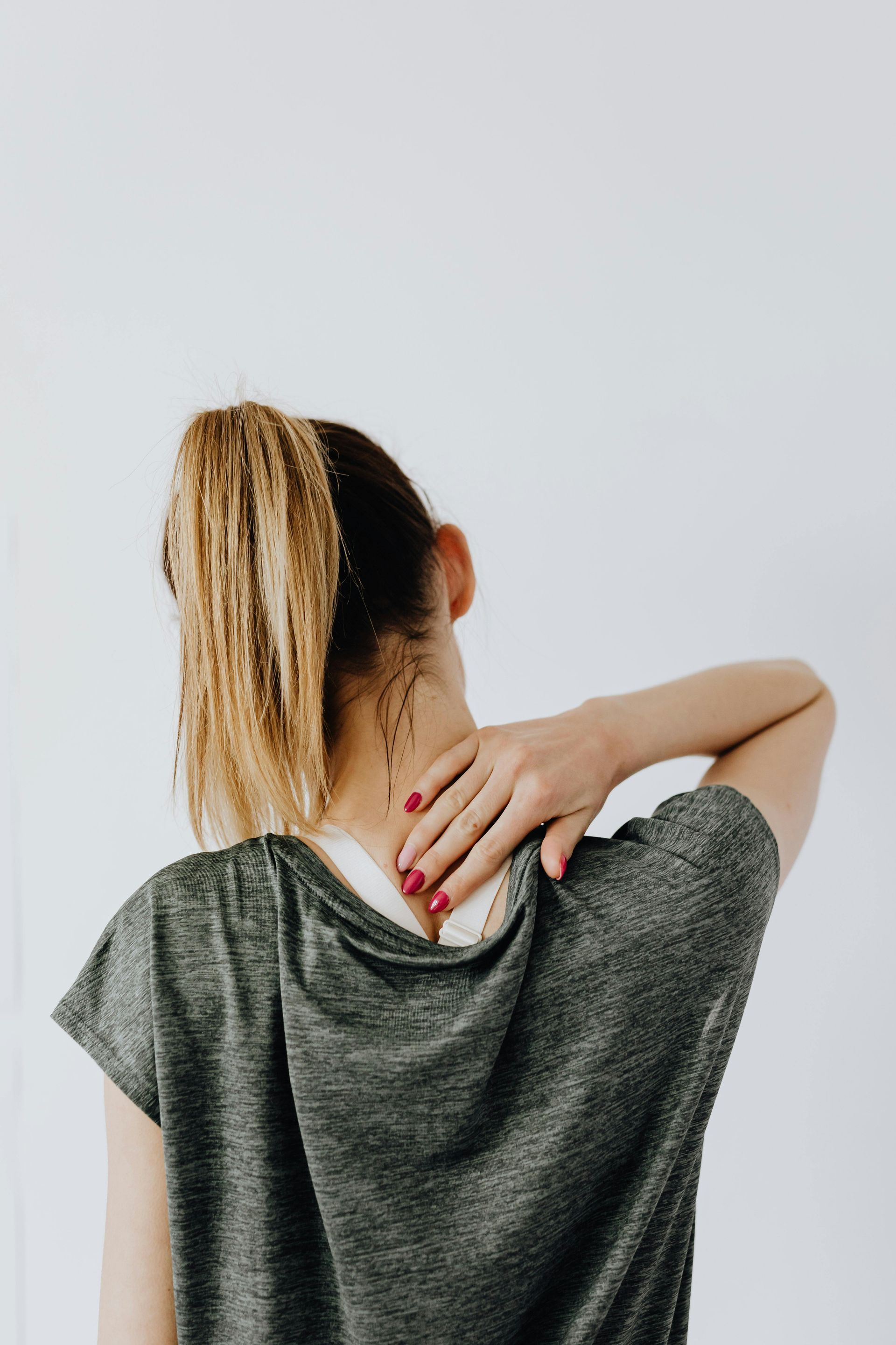 A woman is holding her neck with her hand.