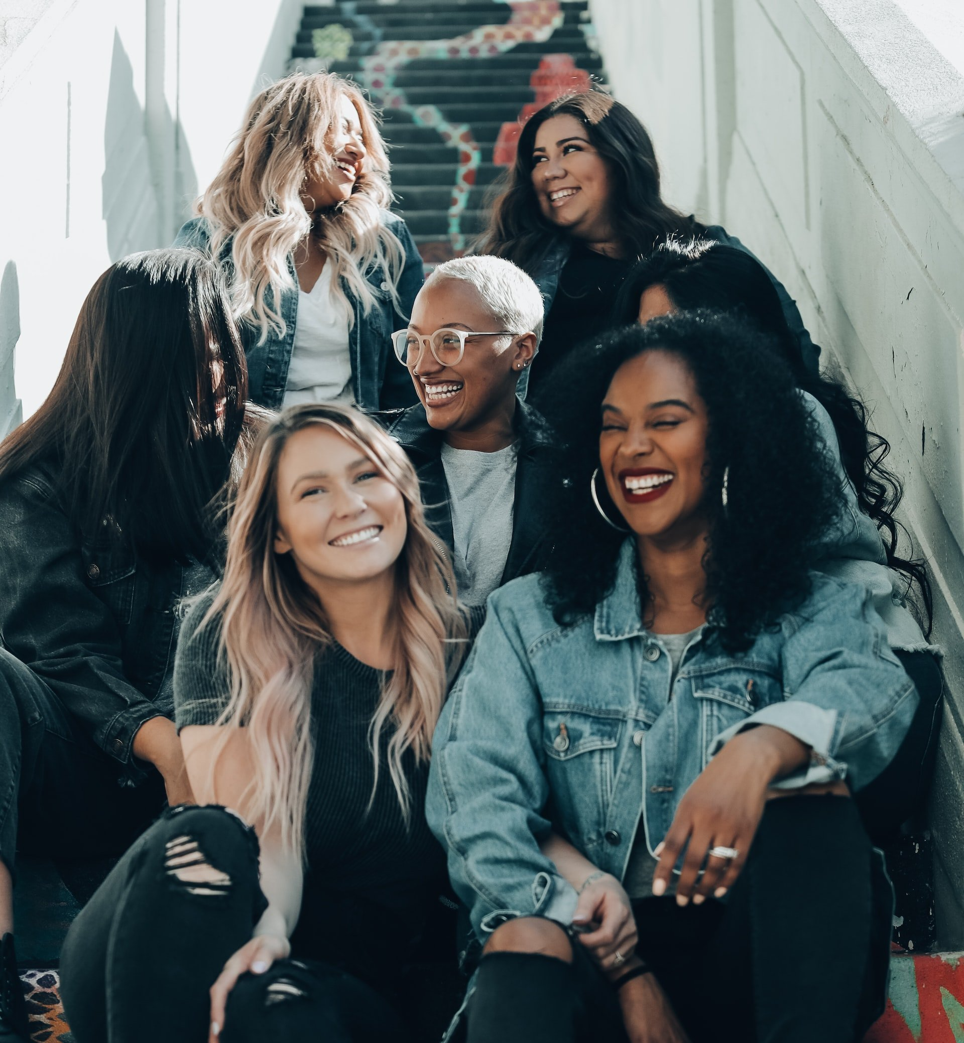 A group of women are sitting on a set of stairs and smiling.
