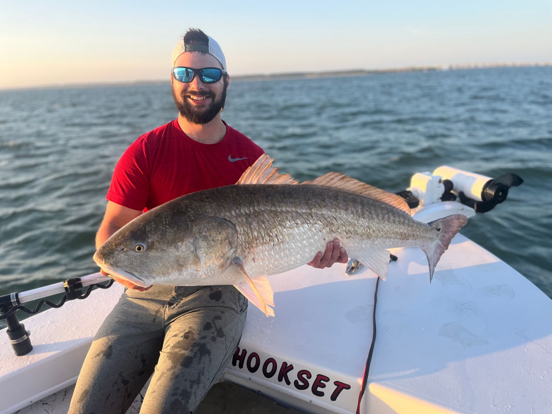 A man is sitting on a boat holding a large fish.
