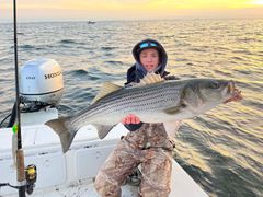 A man is holding a large fish on a boat in the ocean.
