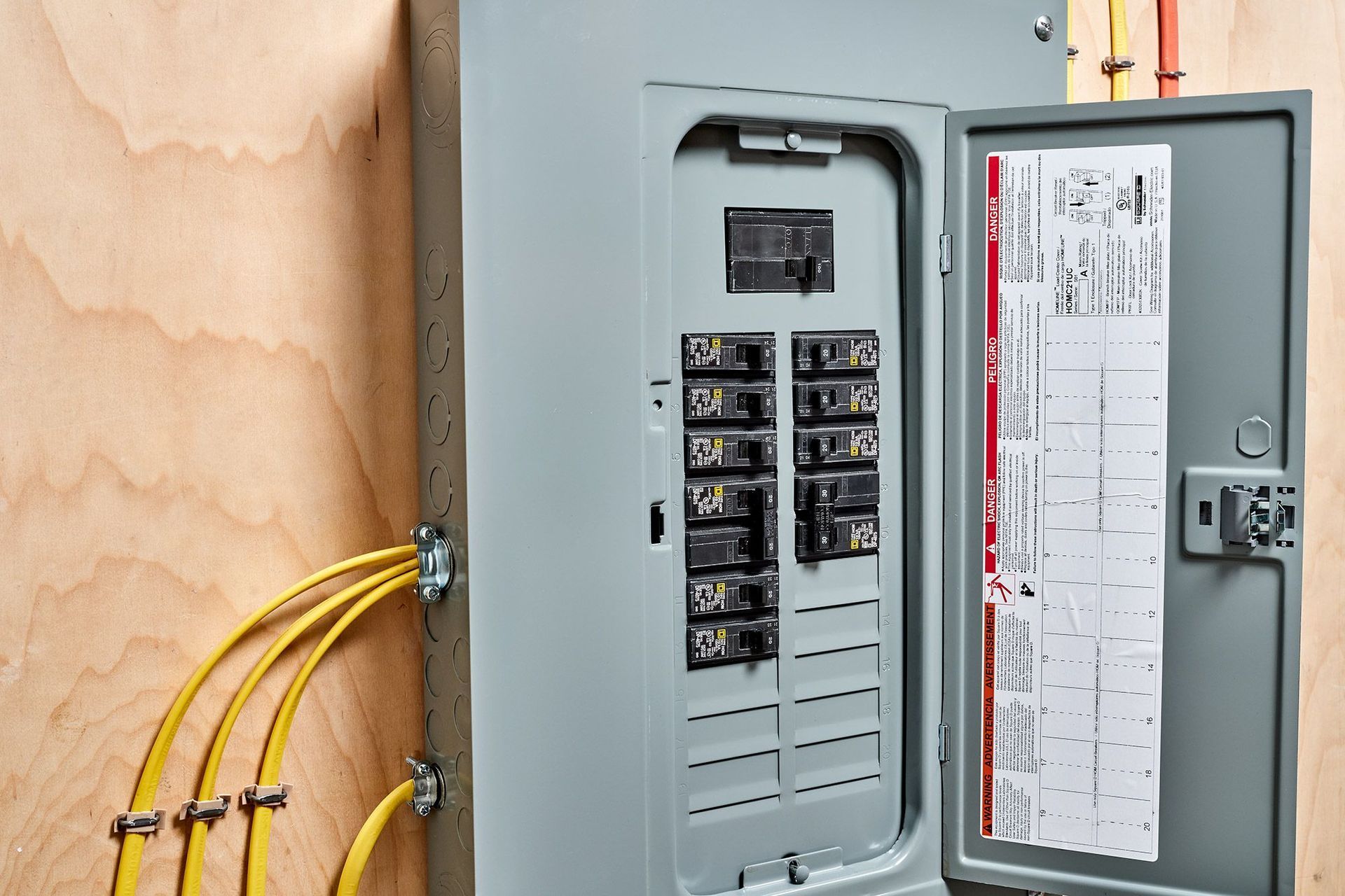 A close up of an electrical box on a wooden wall with the door open.