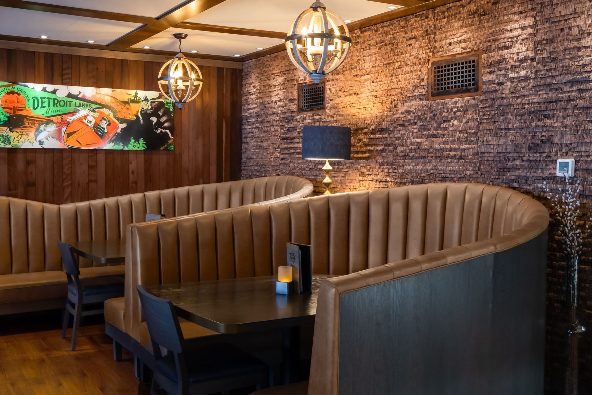 A restaurant with tables and chairs and a brick wall.