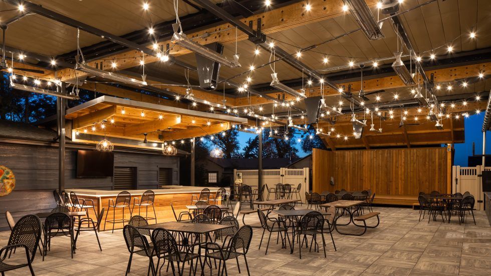 A large room with tables and chairs and string lights hanging from the ceiling.