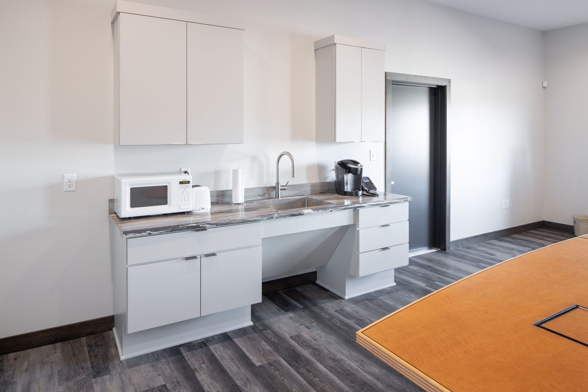 A kitchen with a sink , microwave , and coffee maker.