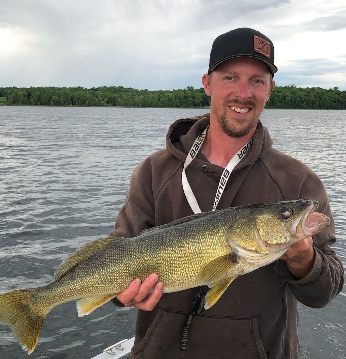 A man is holding a large fish in his hands on a boat.