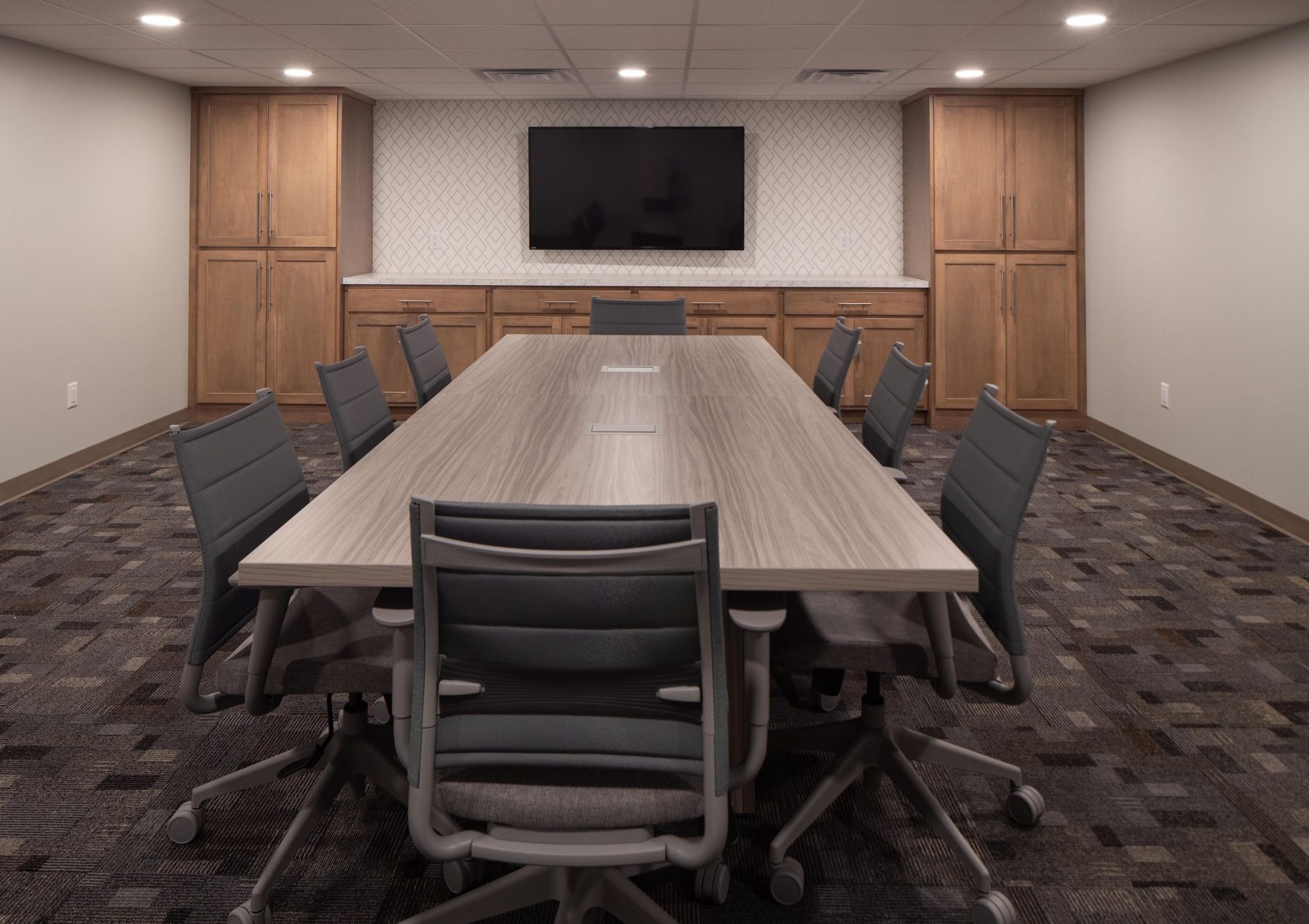A conference room with a long table and chairs and a flat screen tv.