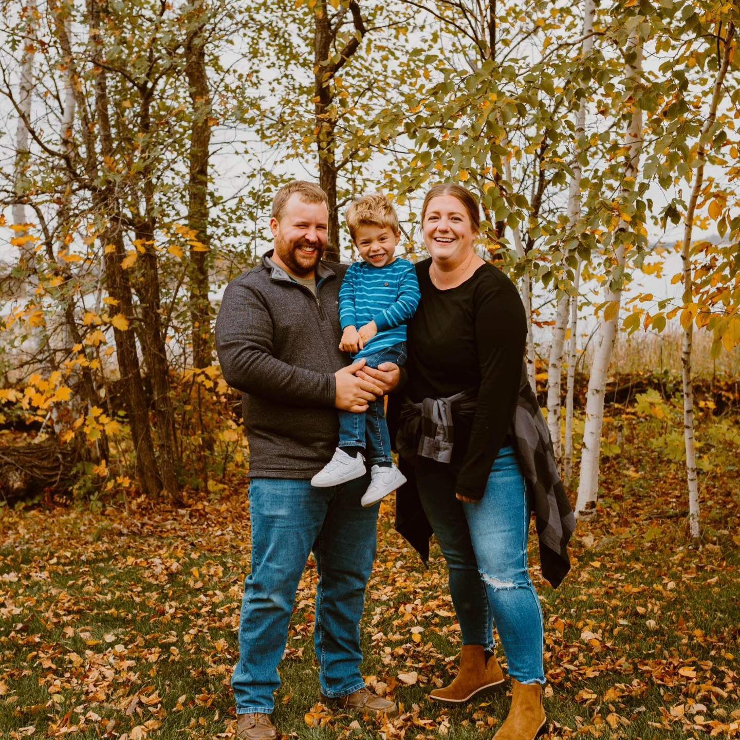 A family is posing for a picture in the woods.