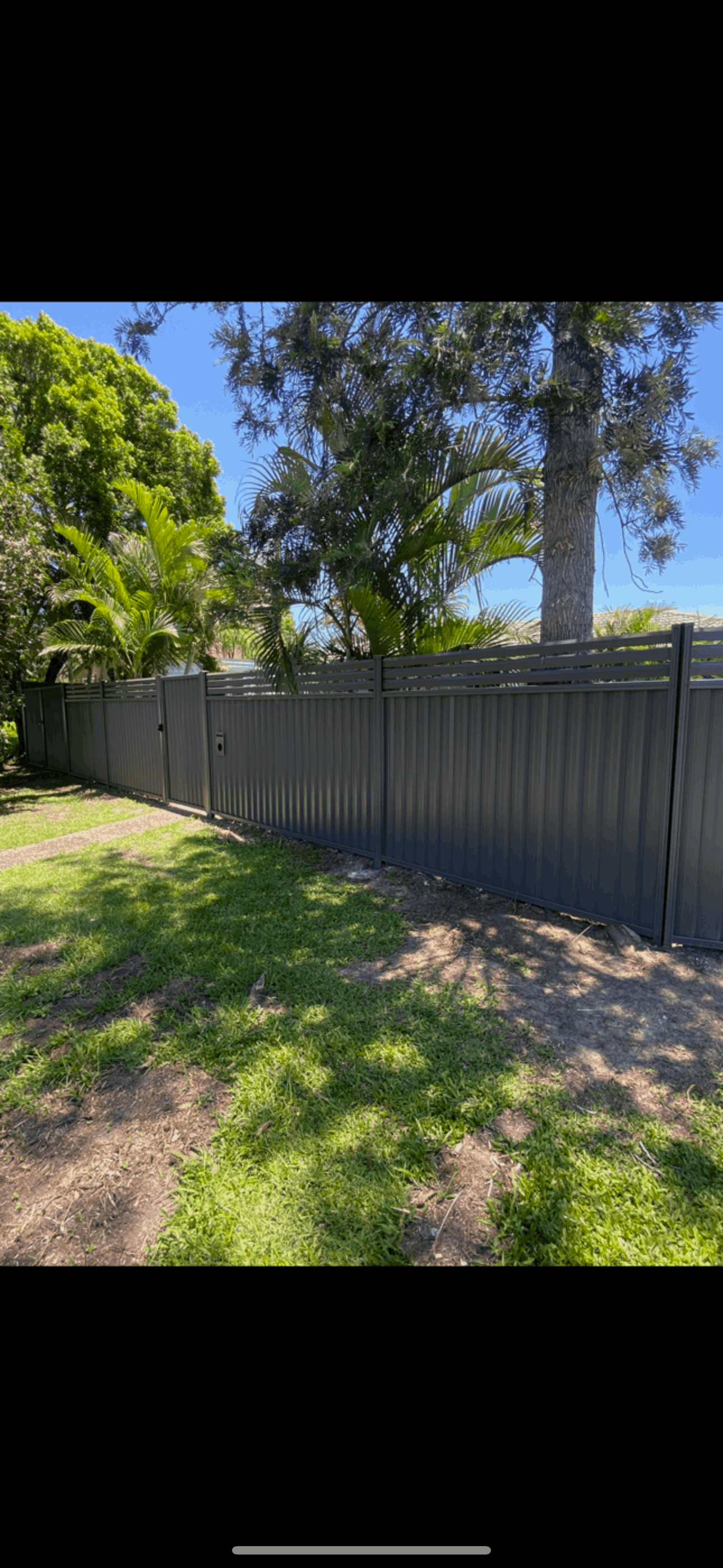 A white wooden fence with a gate in front of a house.
