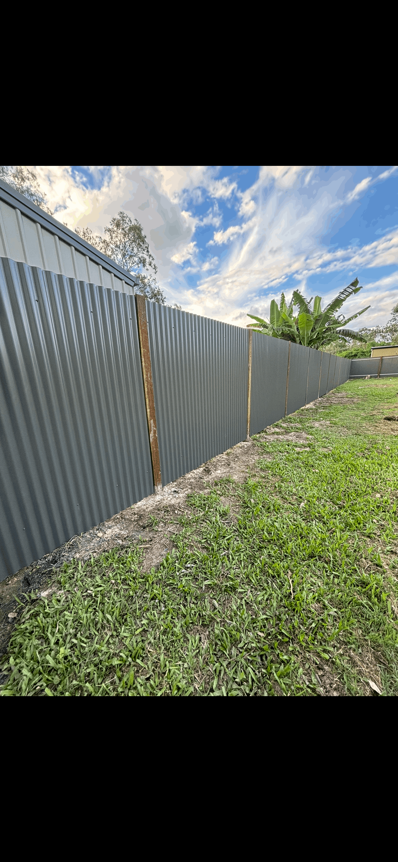 A fence with a gate in front of a brick building.