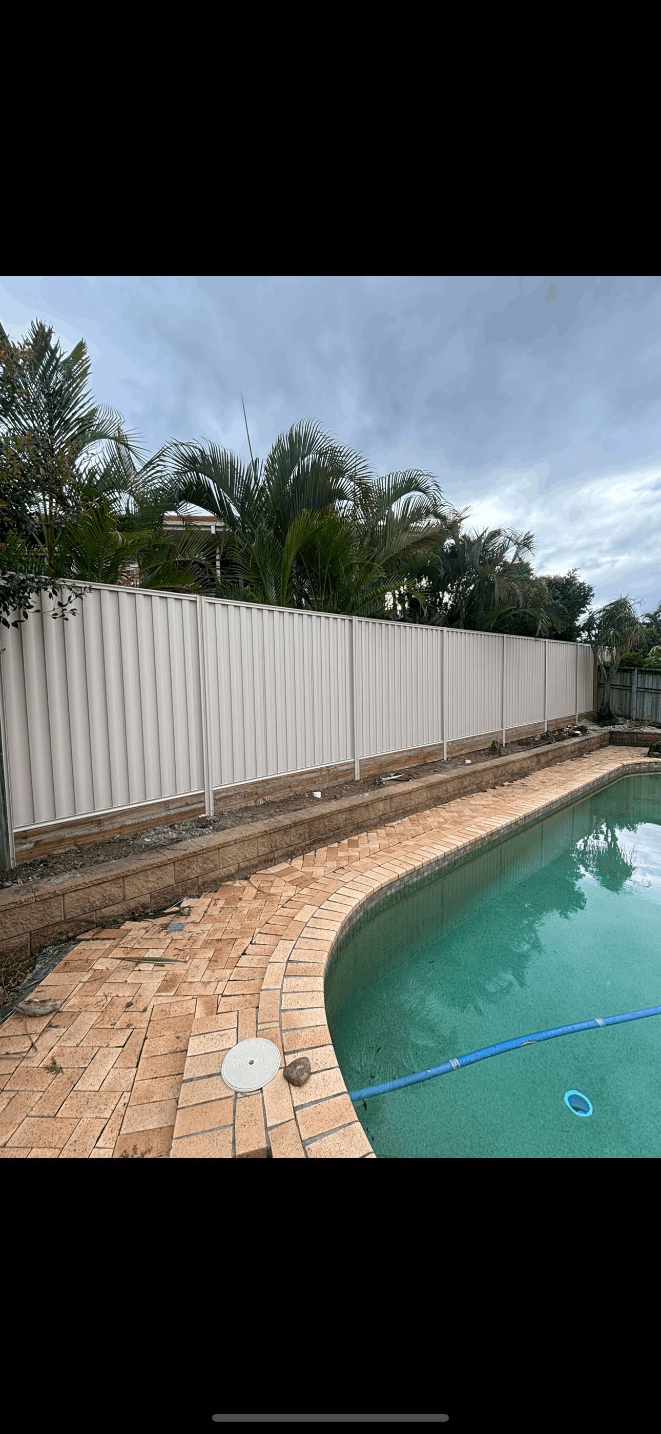 A wooden fence in a backyard with a house in the background.