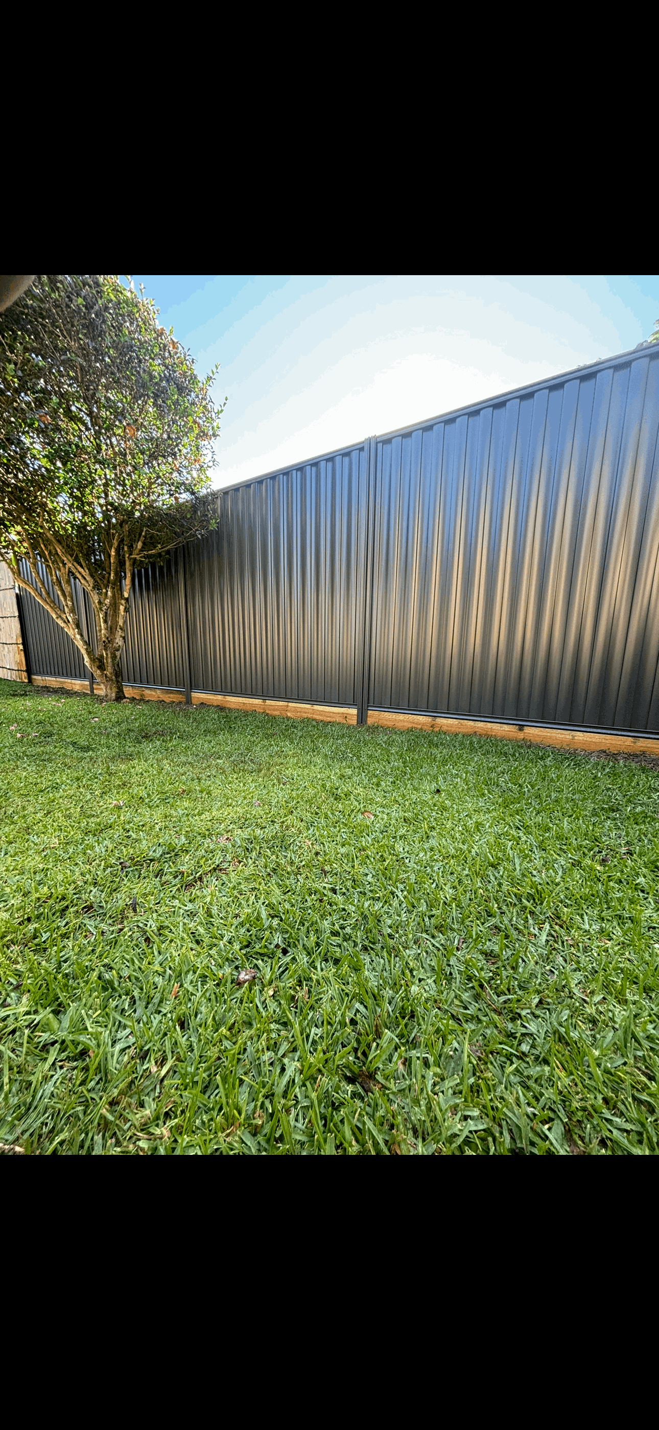 A white fence surrounds a lush green field.