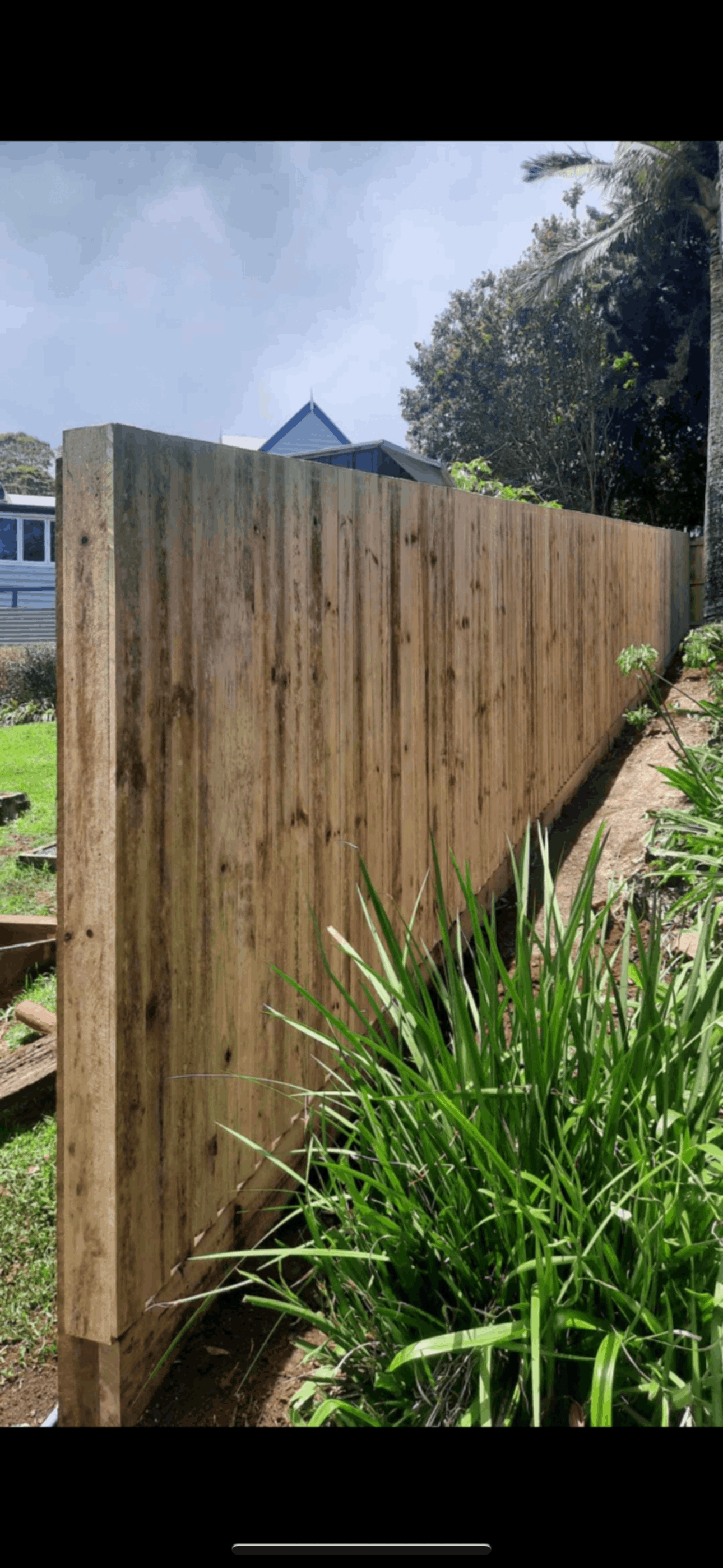 A wooden fence is being built in front of a building in a parking lot.