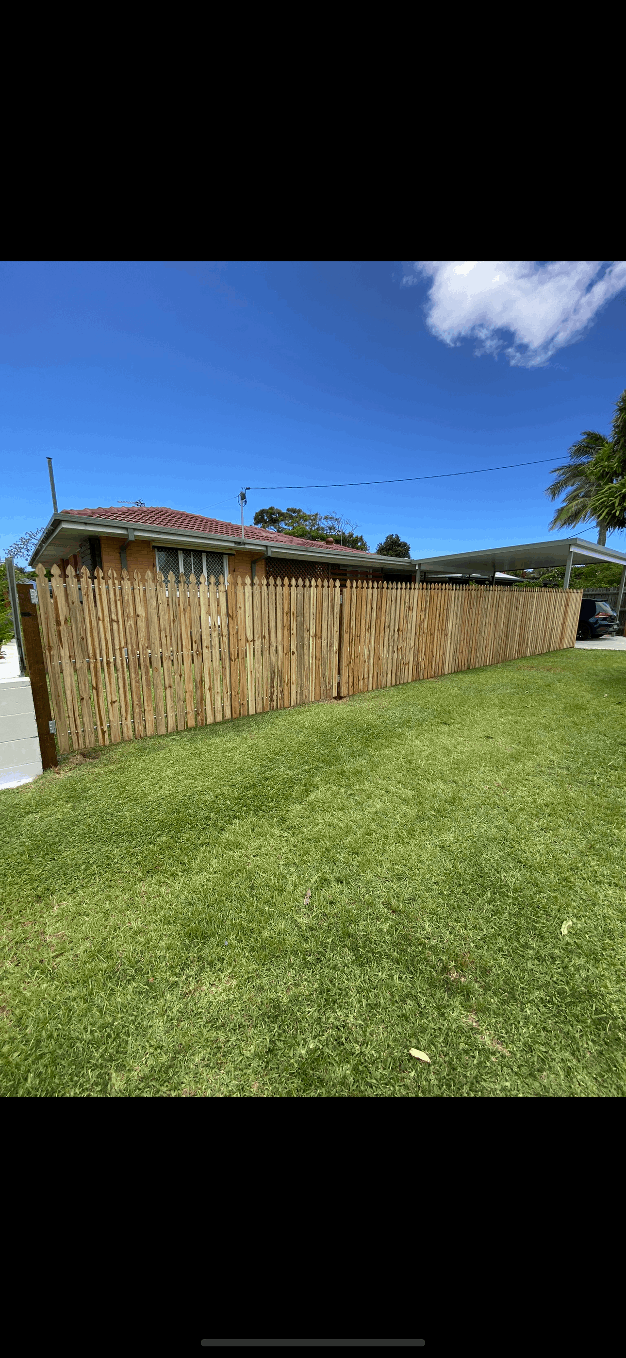 A wooden fence is sitting in the grass in front of a house.