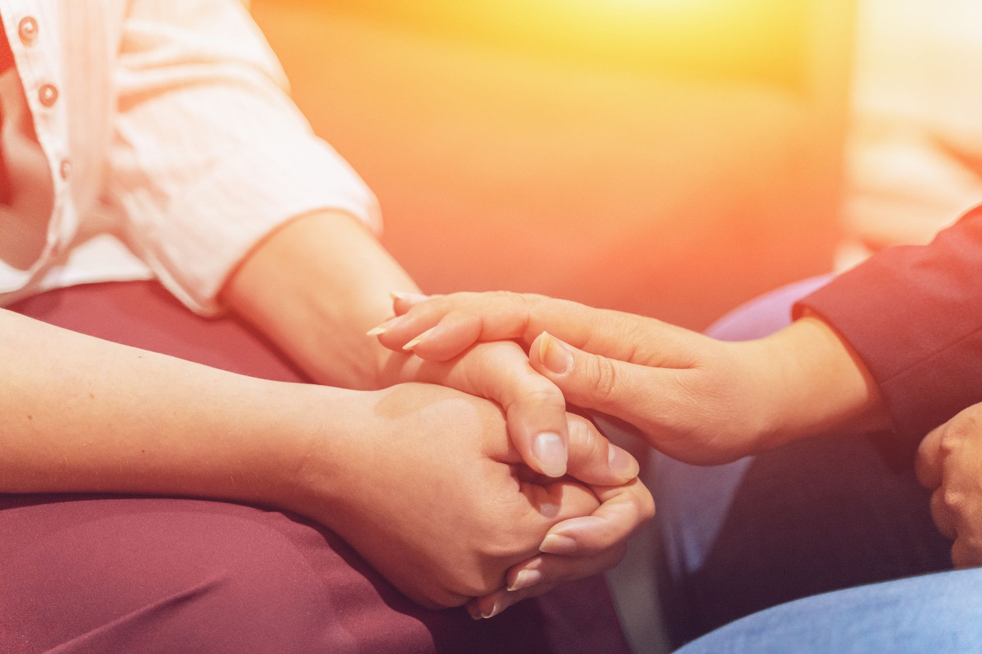 Hands clasped in supportive gesture, warm sunlight.