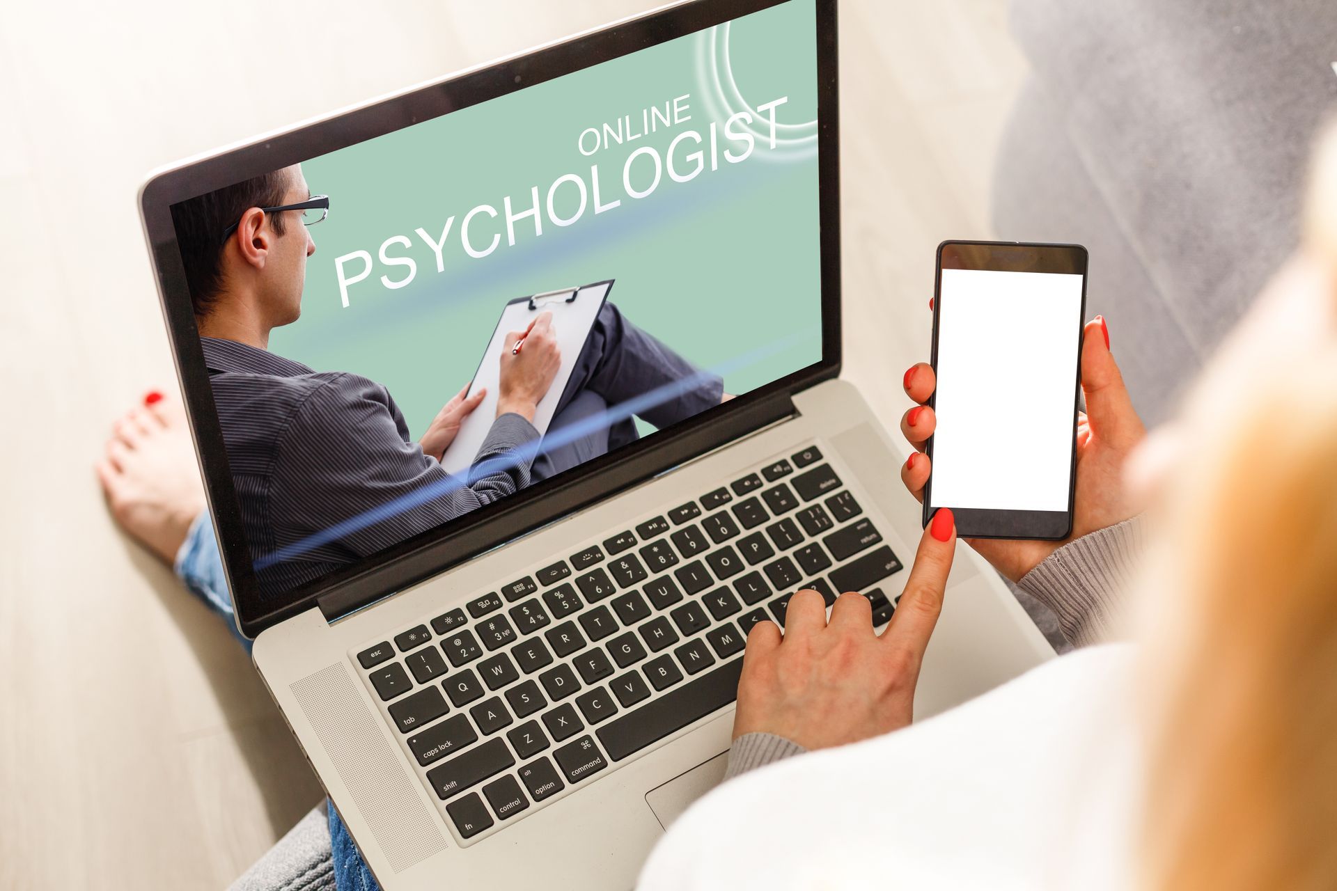 Person using laptop and smartphone for online therapy session. Person using laptop and smartphone for online therapy session.