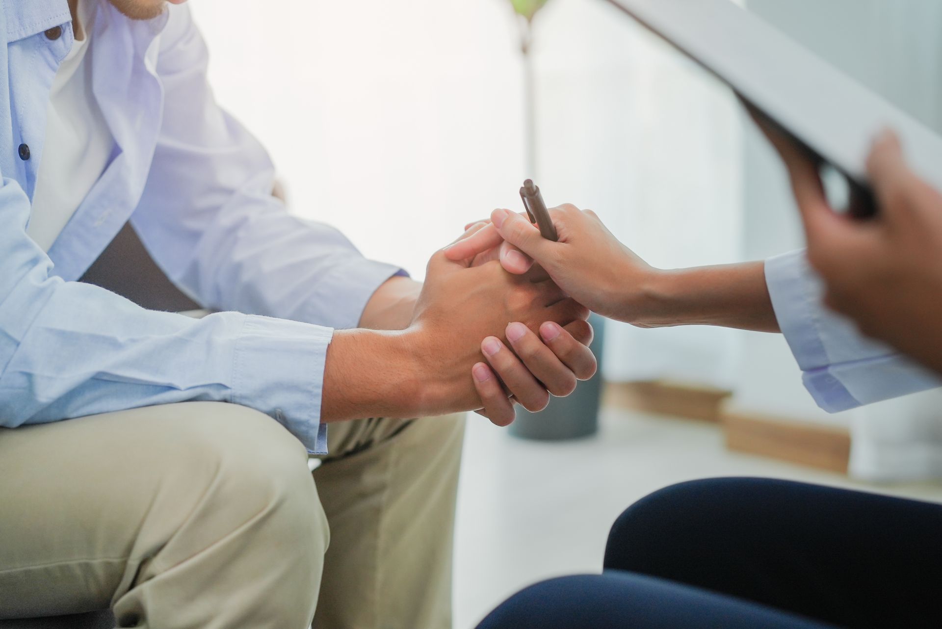 Therapist holding a patient's hands, providing comfort and support during a counseling session.