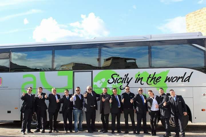 Un gruppo di uomini in piedi davanti a un autobus con la scritta
