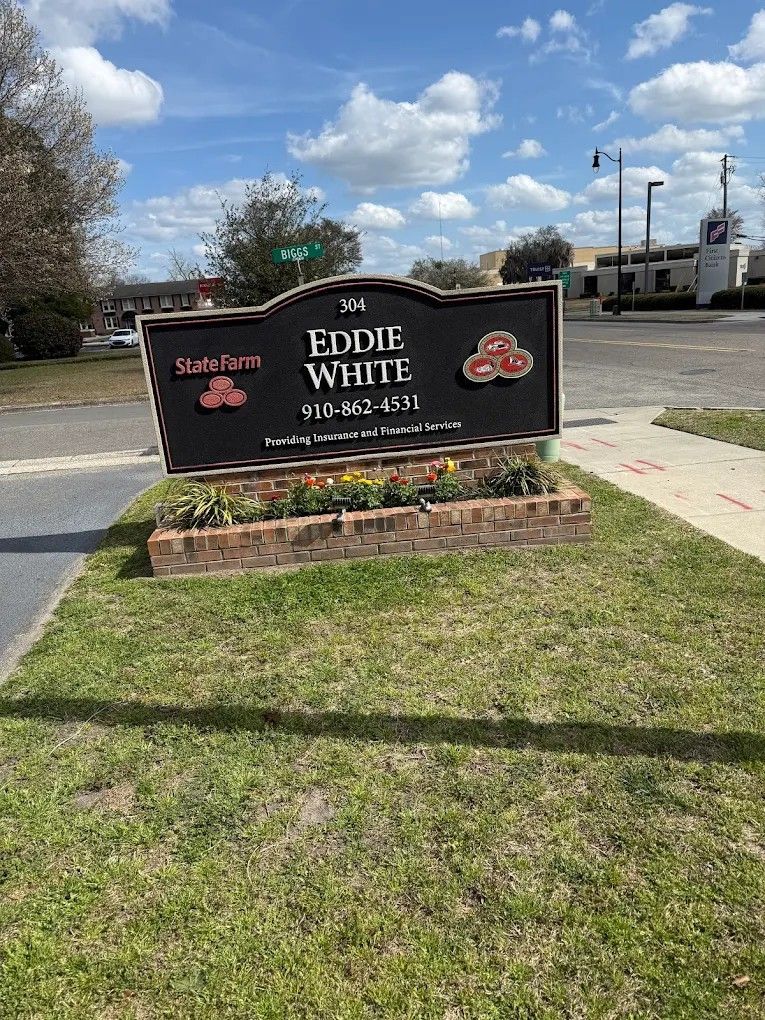 Black sign for Eddie White in front of a brick-and-stone business building under a blue sky