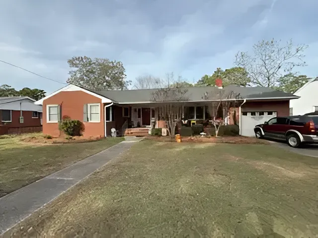 Single-story brick house with covered porch, front yard, and a red truck parked in the driveway.