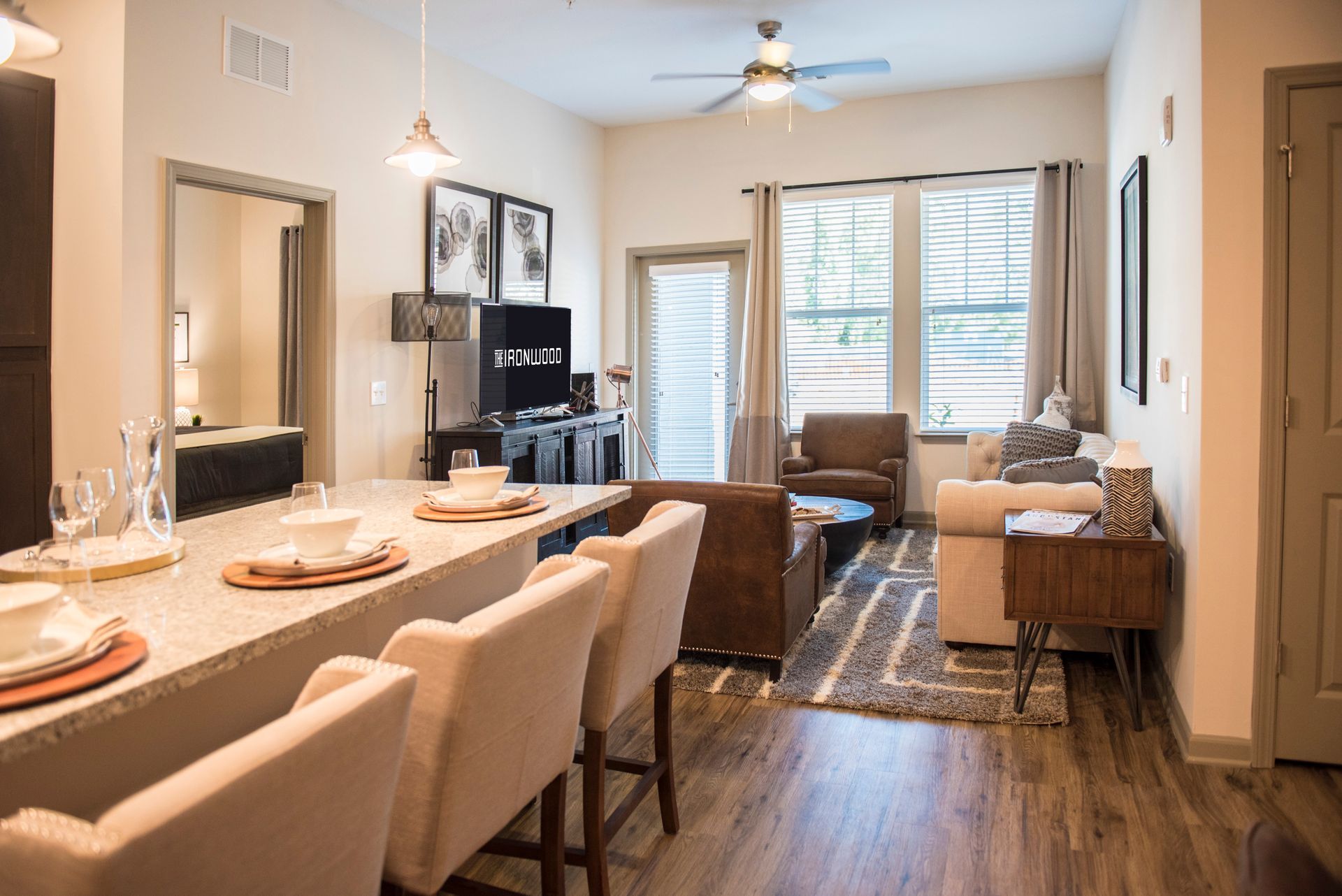 Modern apartment living room with bar seating, neutral tones, and outdoor access at Ironwood Apartment Homes.
