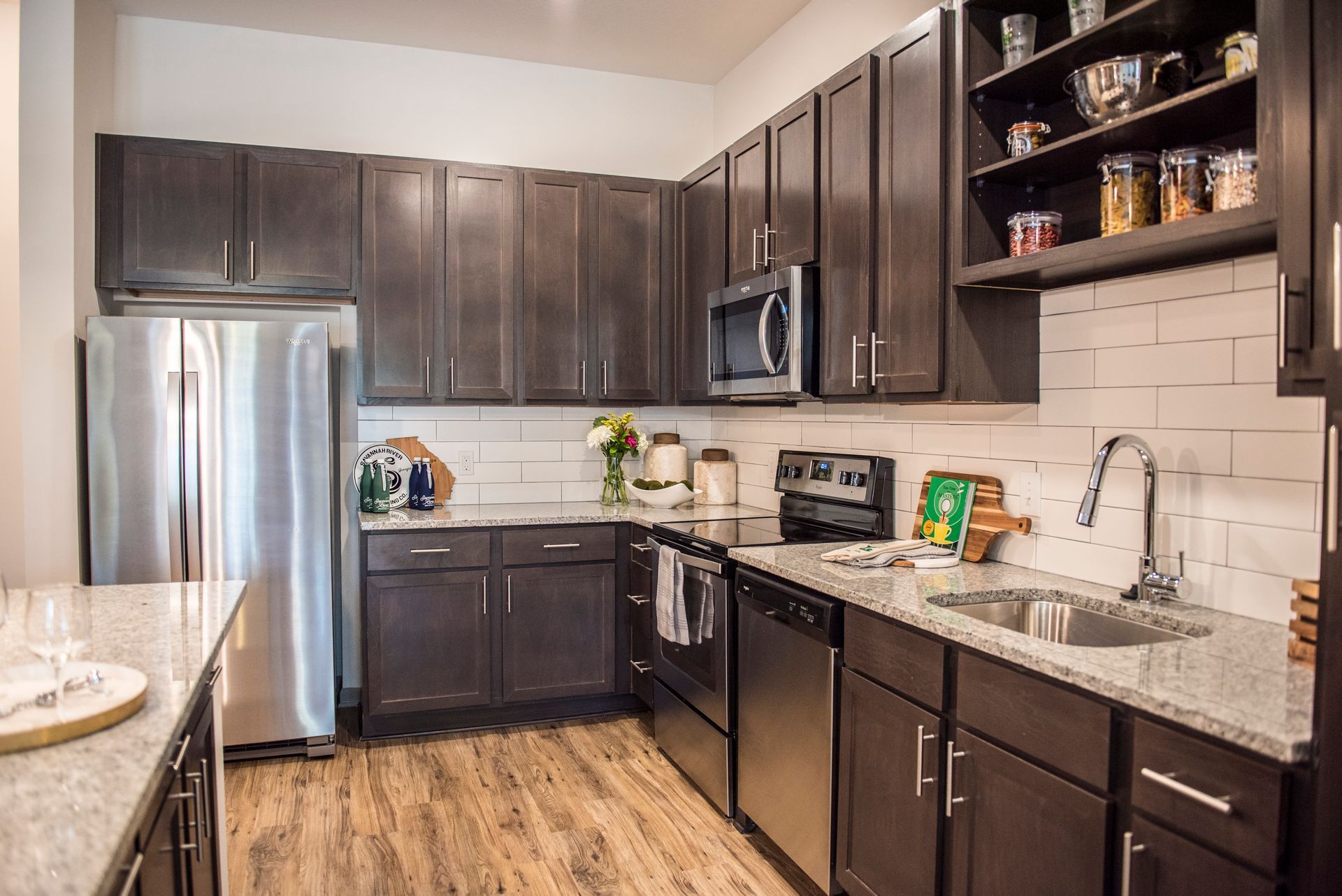 Modern kitchen with stainless steel appliances, dark cabinets, and white subway tile backsplashs at Ironwood Apartment Homes.