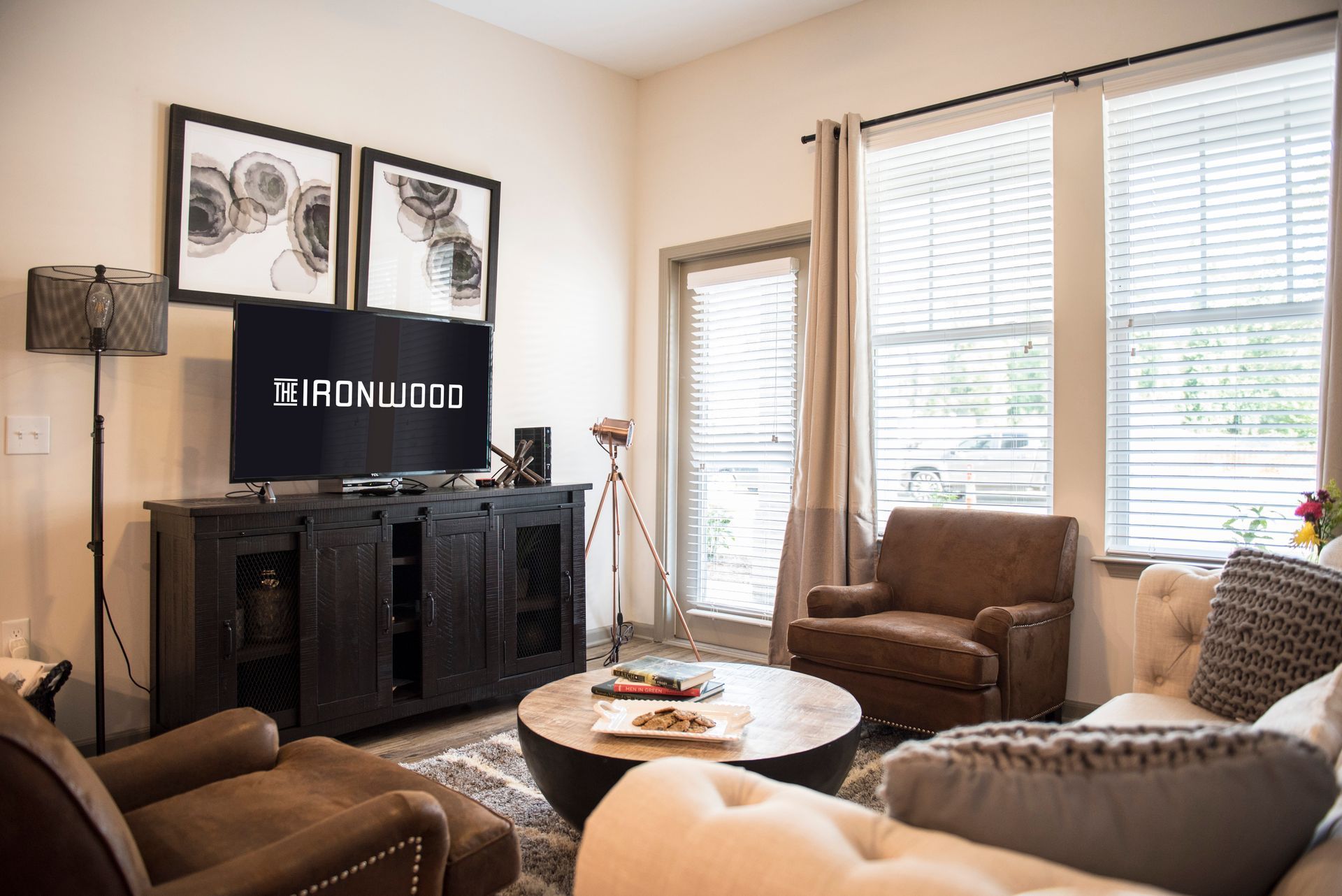 Living room with TV, seating, and a window at Ironwood Apartment Homes.