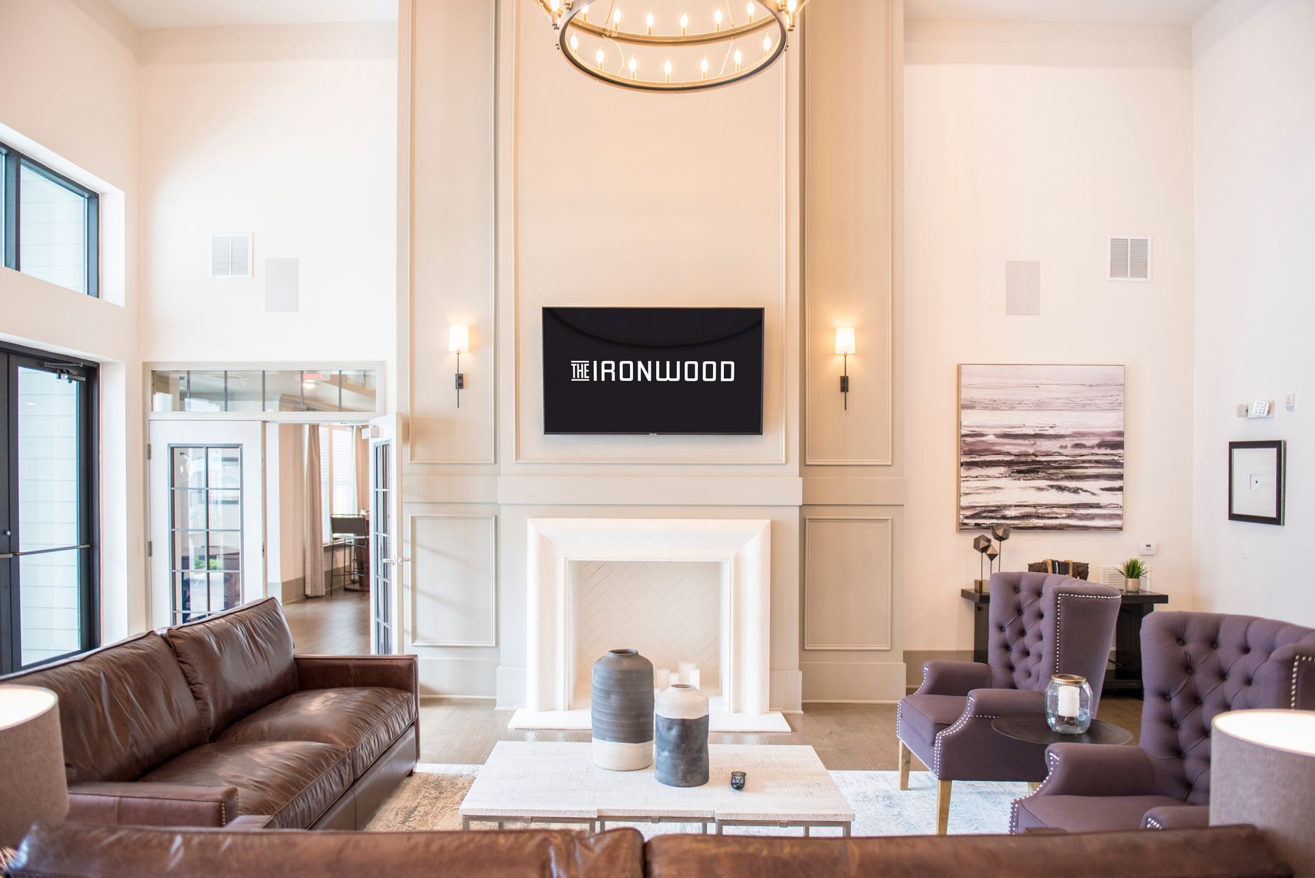A modern living room with leather furniture, a fireplace, and a TV; neutral colors at Ironwood Apartment Homes.