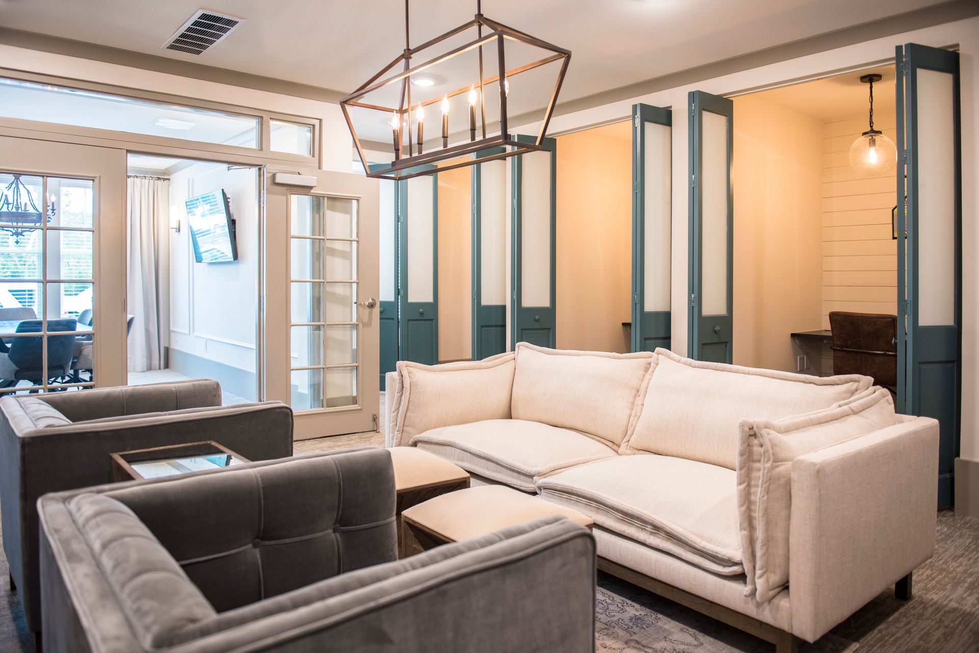 Living room with sofa, chairs, and doors, with an open door to a room with a desk at Ironwood Apartment Homes.