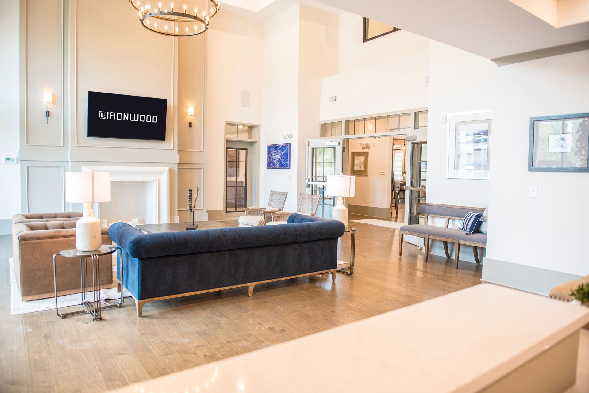 Spacious lobby with blue sofa, fireplace, and reception desk. Light wood floors, neutral tones, and elegant fixtures at Ironwood Apartment Homes.