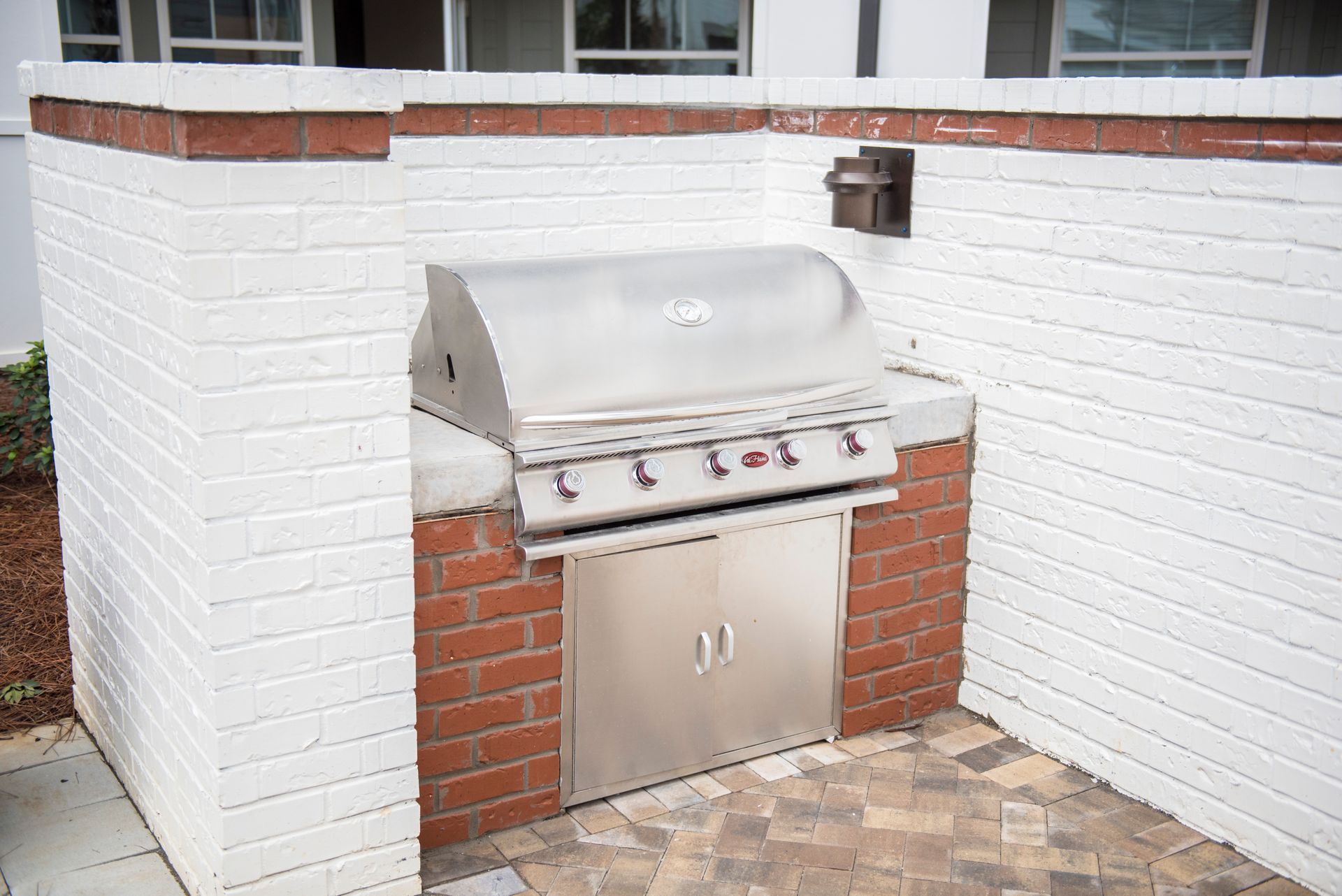Brick-built outdoor kitchen with a stainless steel grill. White-painted brick walls frame the red brick base at Ironwood Apartment Homes.