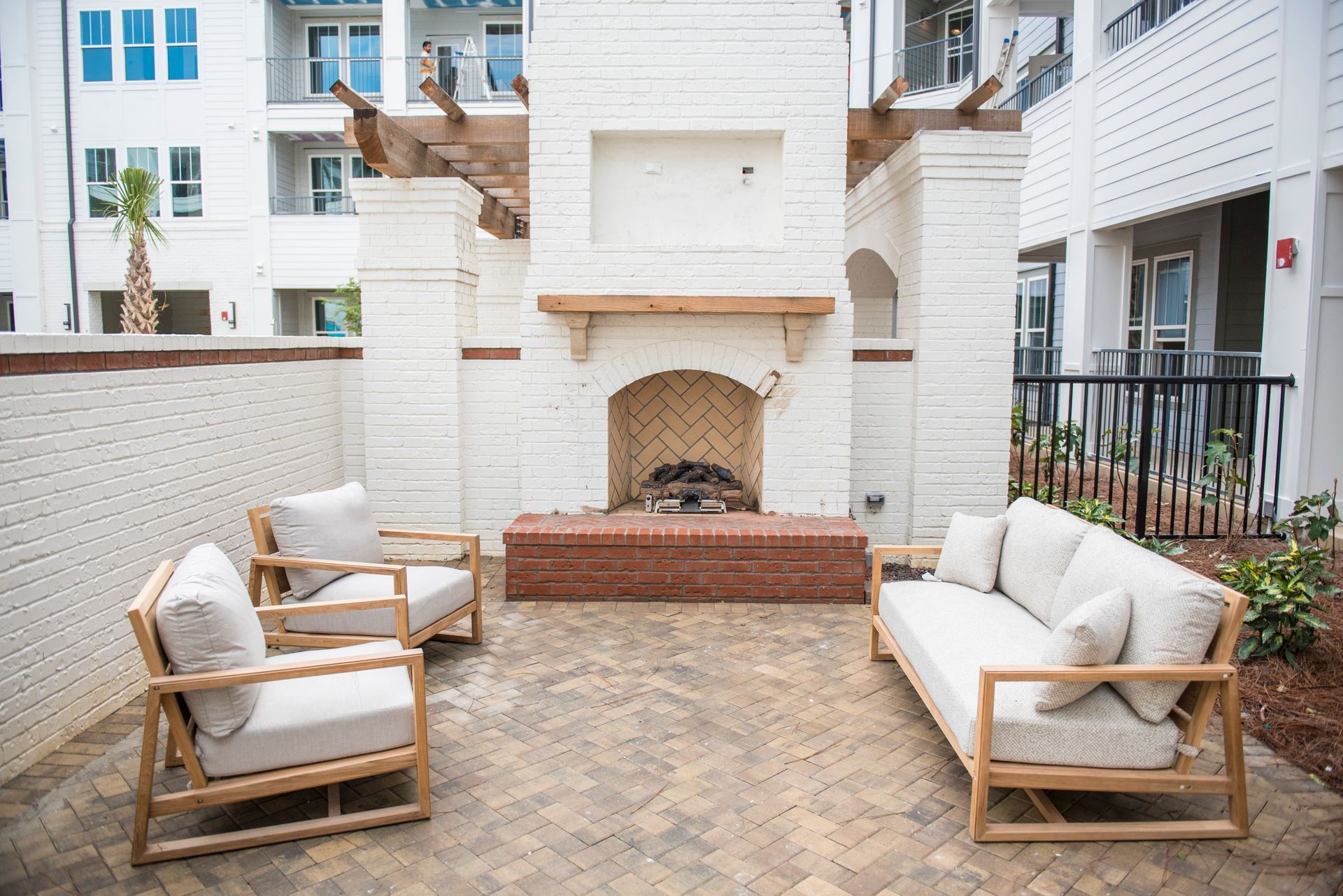 Outdoor seating area with a white brick fireplace and wooden furniture at Ironwood Apartment Homes.