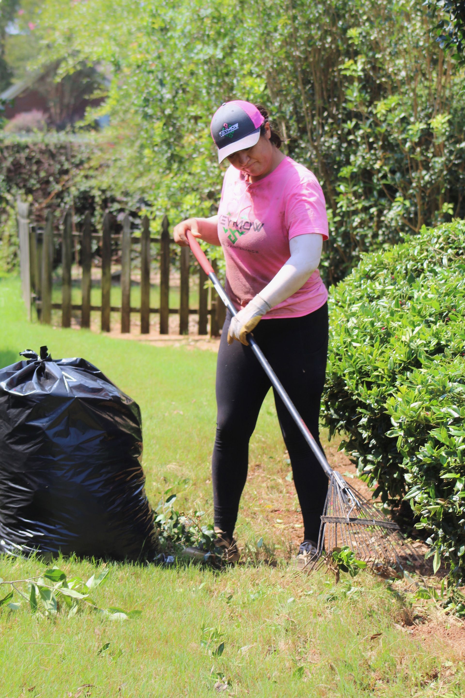 Person raking leaves beside a large black yard-waste bag in a grassy yard