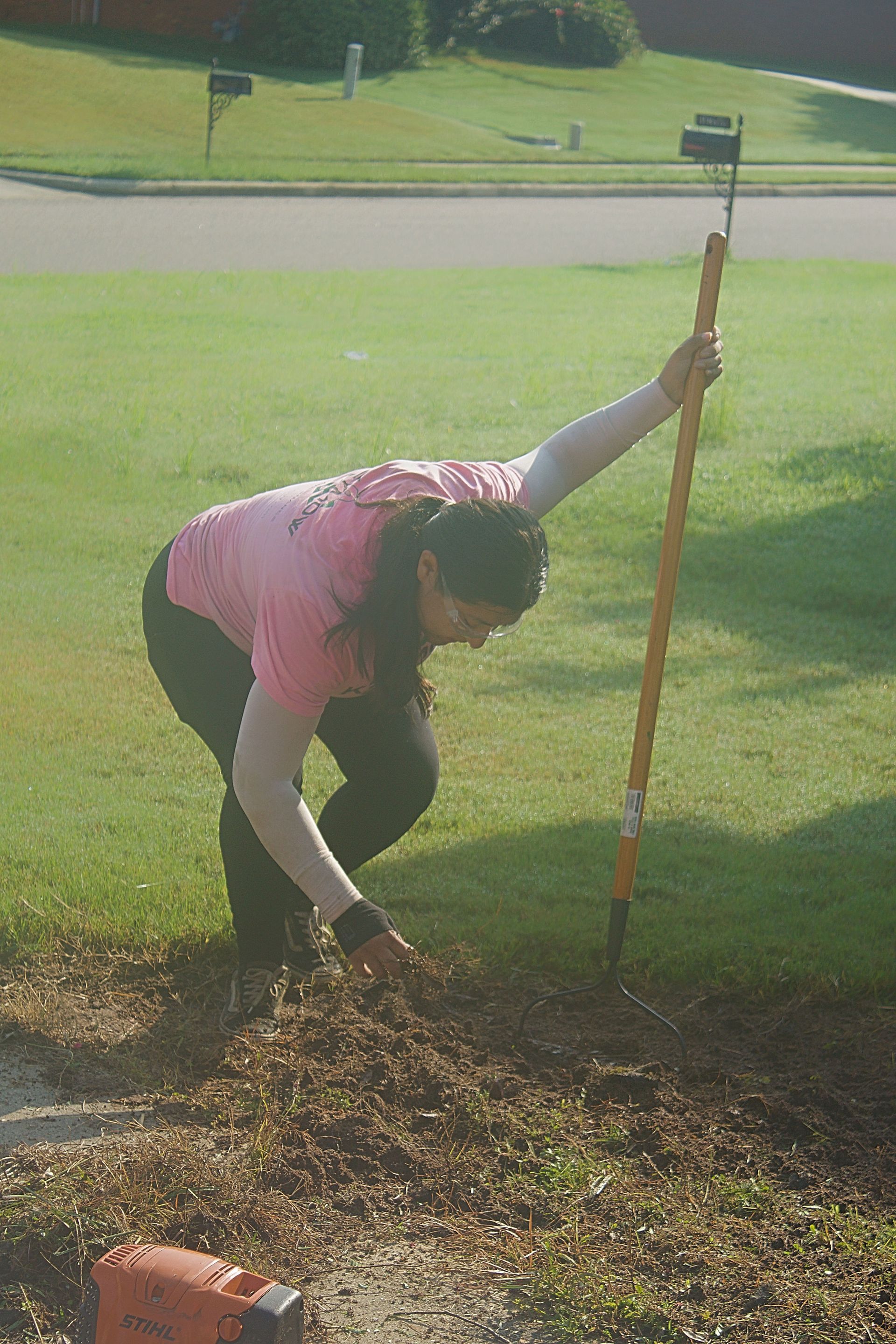 Person raking leaves on a grassy lawn with a long-handled rake.