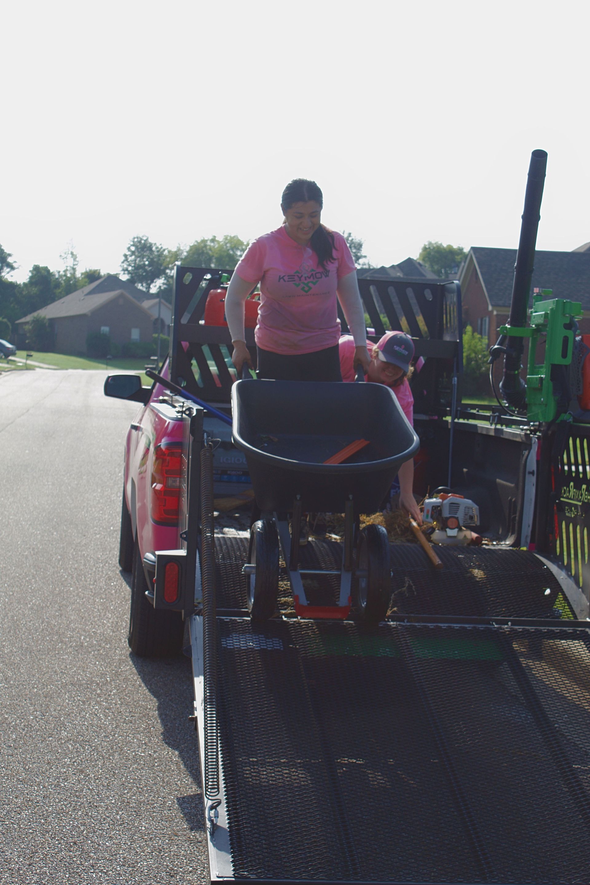 Person standing on a trailer-mounted wheelchair lift being loaded behind a red truck on a road