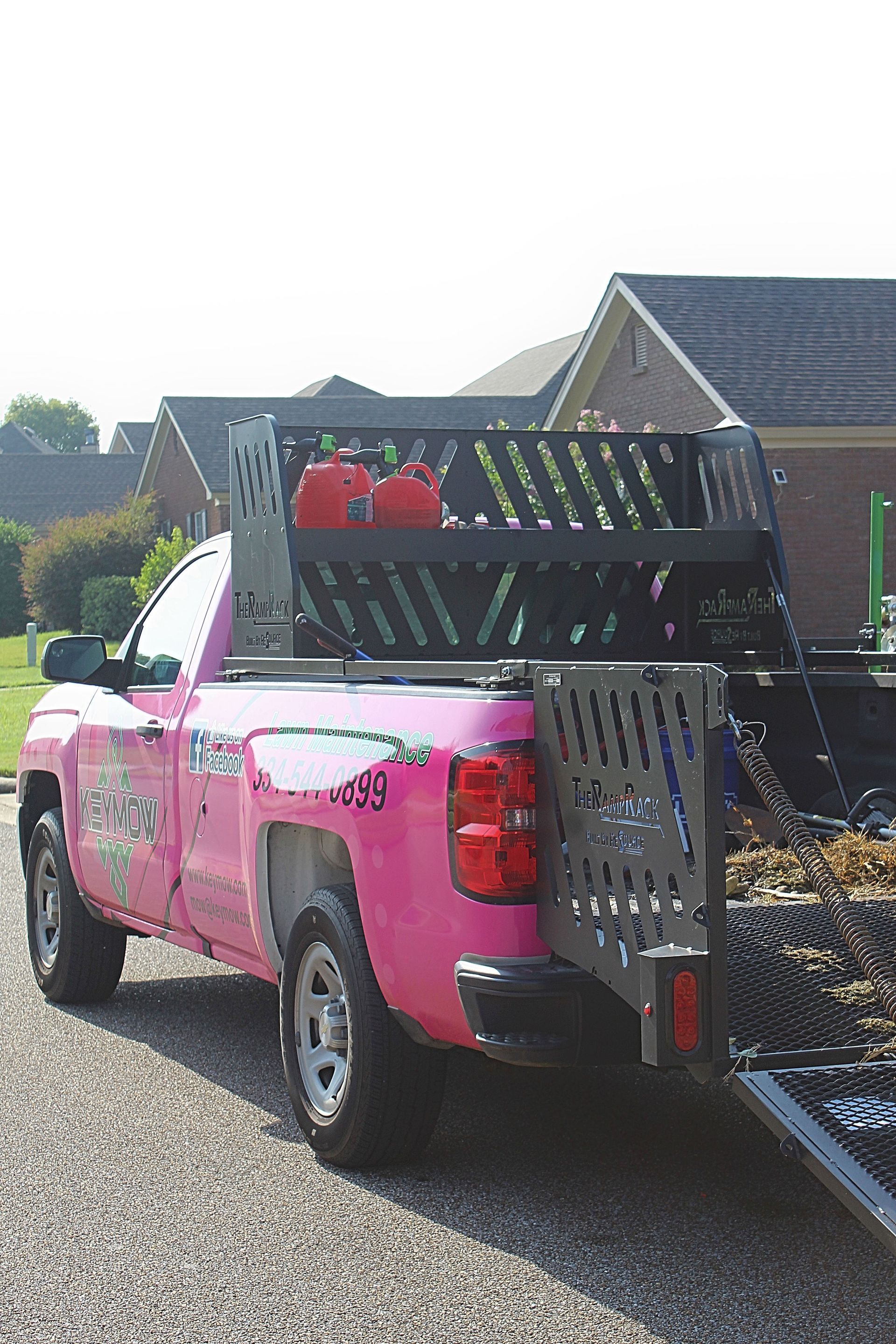 Pink pickup truck loaded with gardening equipment and debris on a residential street