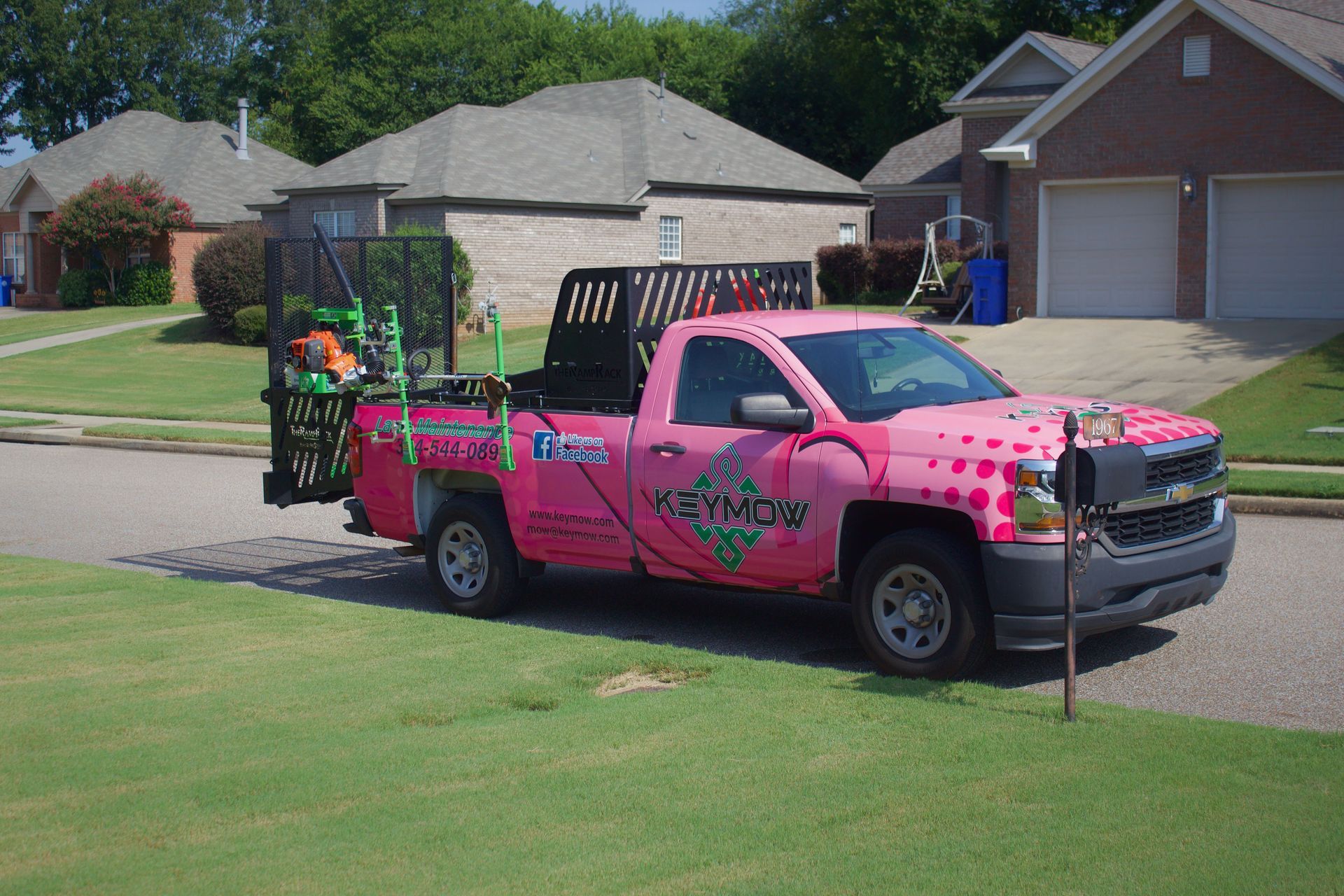 Pink pickup truck with a decorated trailer parked on a suburban street lawn
