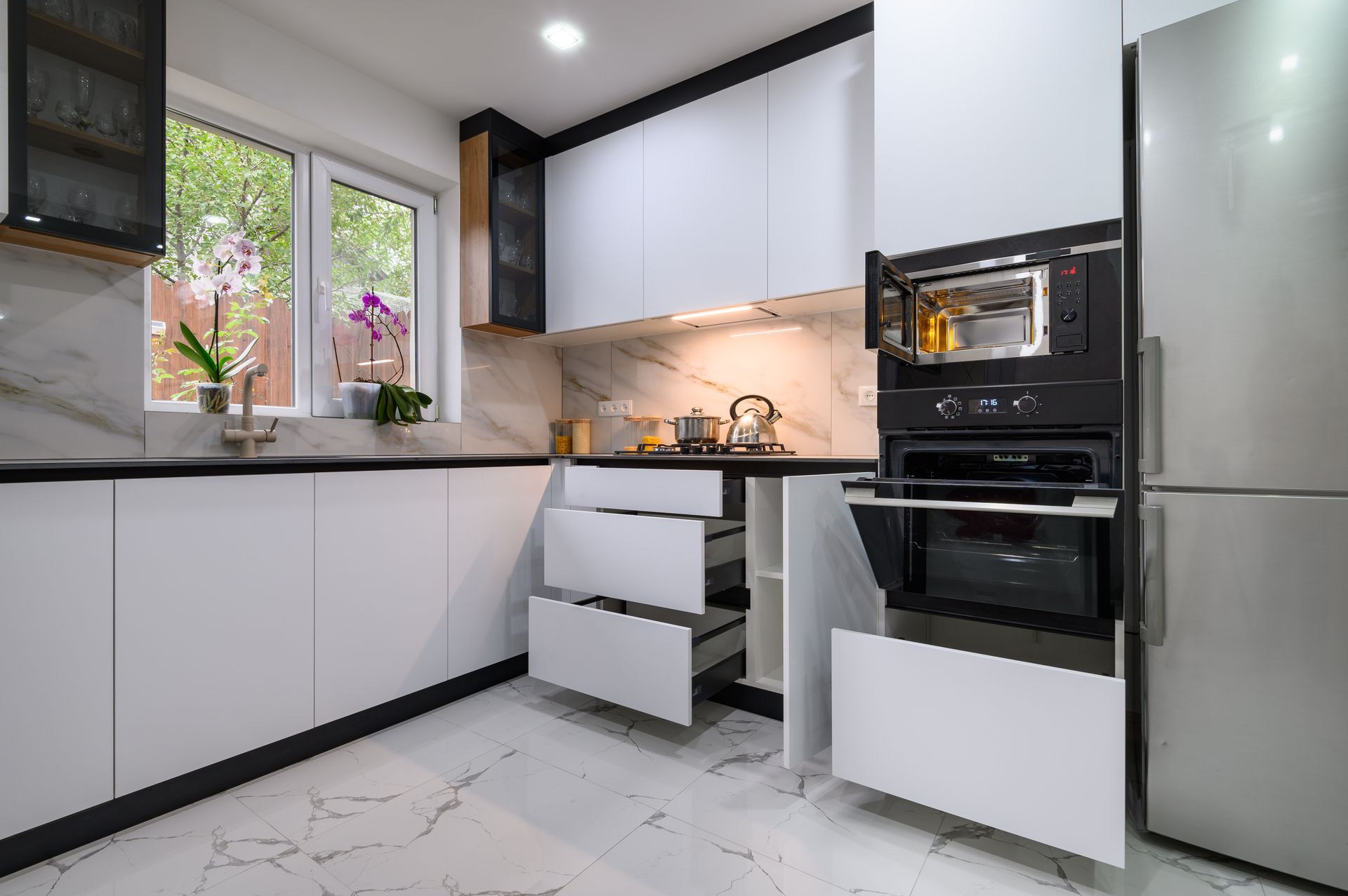 A kitchen with white cabinets , stainless steel appliances , and a refrigerator.
