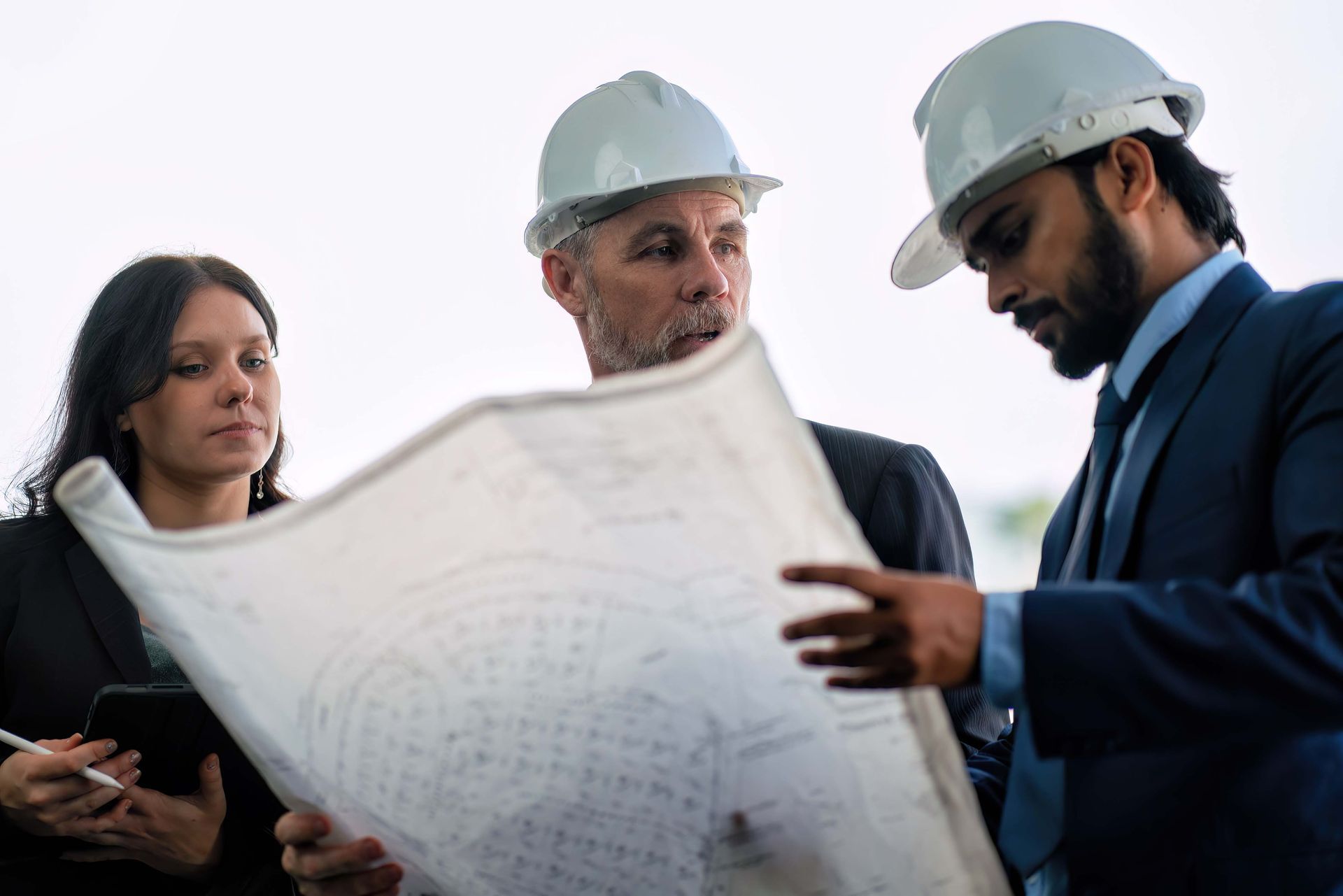A group of people wearing hard hats are looking at a blueprint.