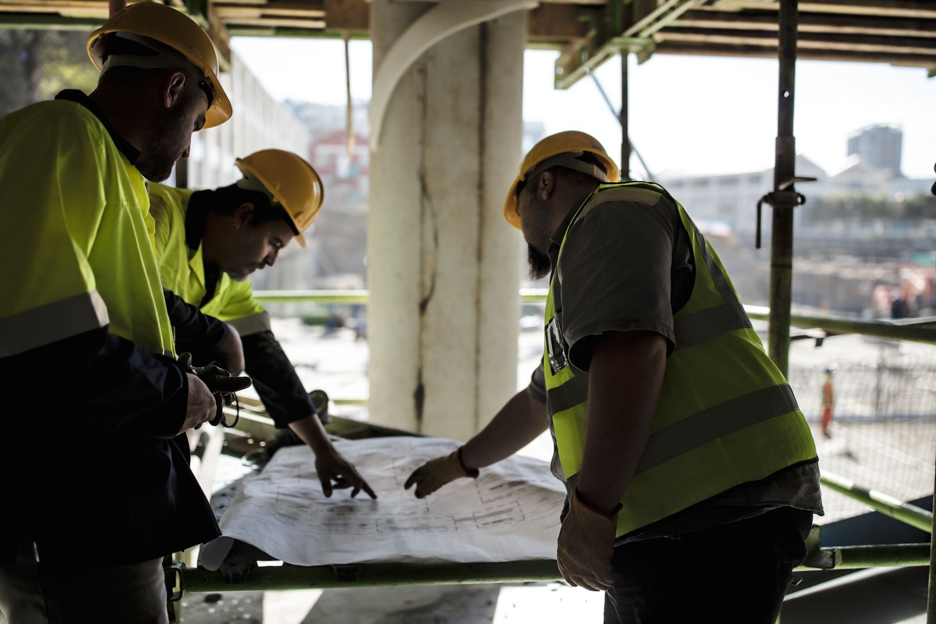 A group of construction workers are looking at a blueprint on a construction site.