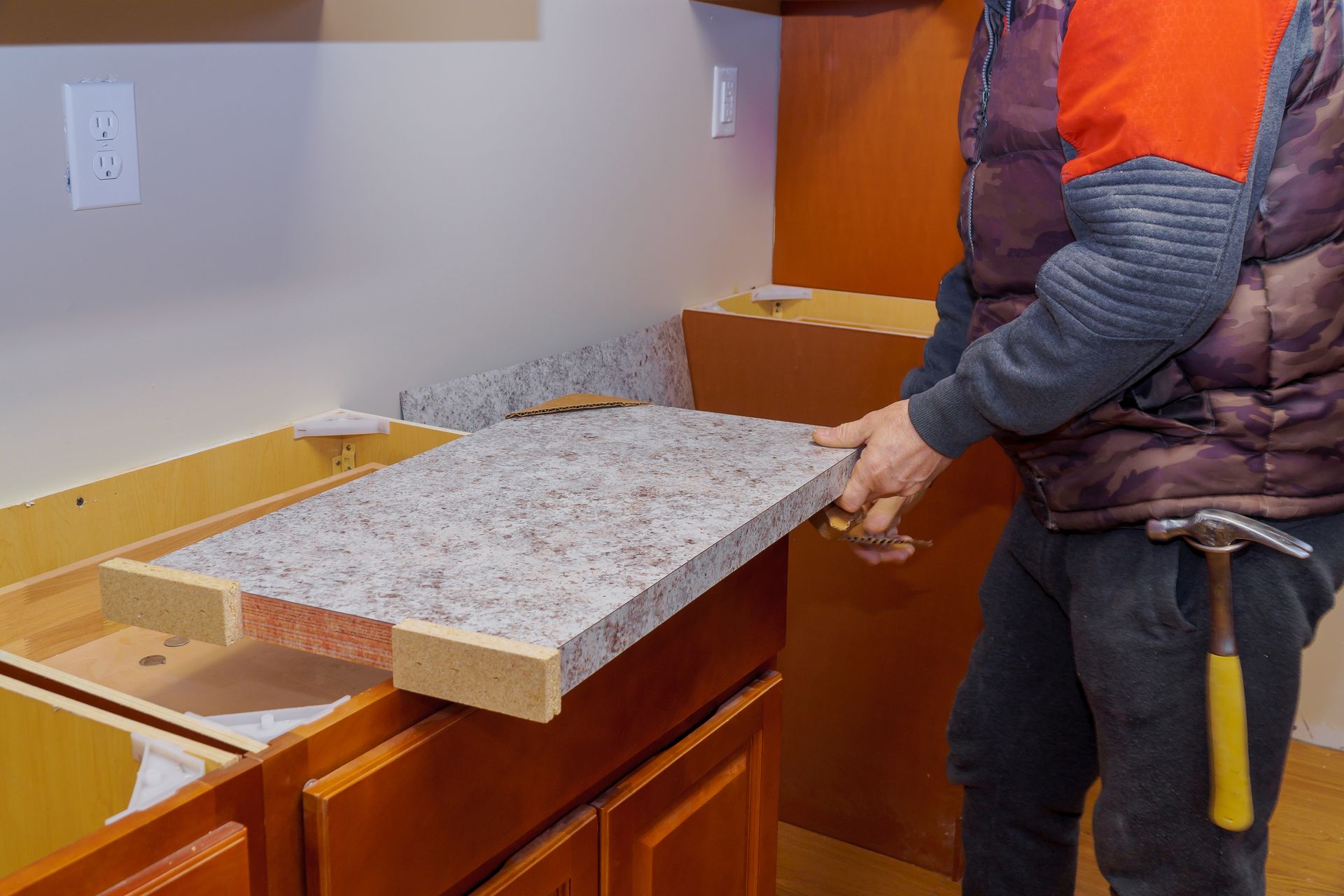 A man is holding a piece of granite on top of a kitchen counter.