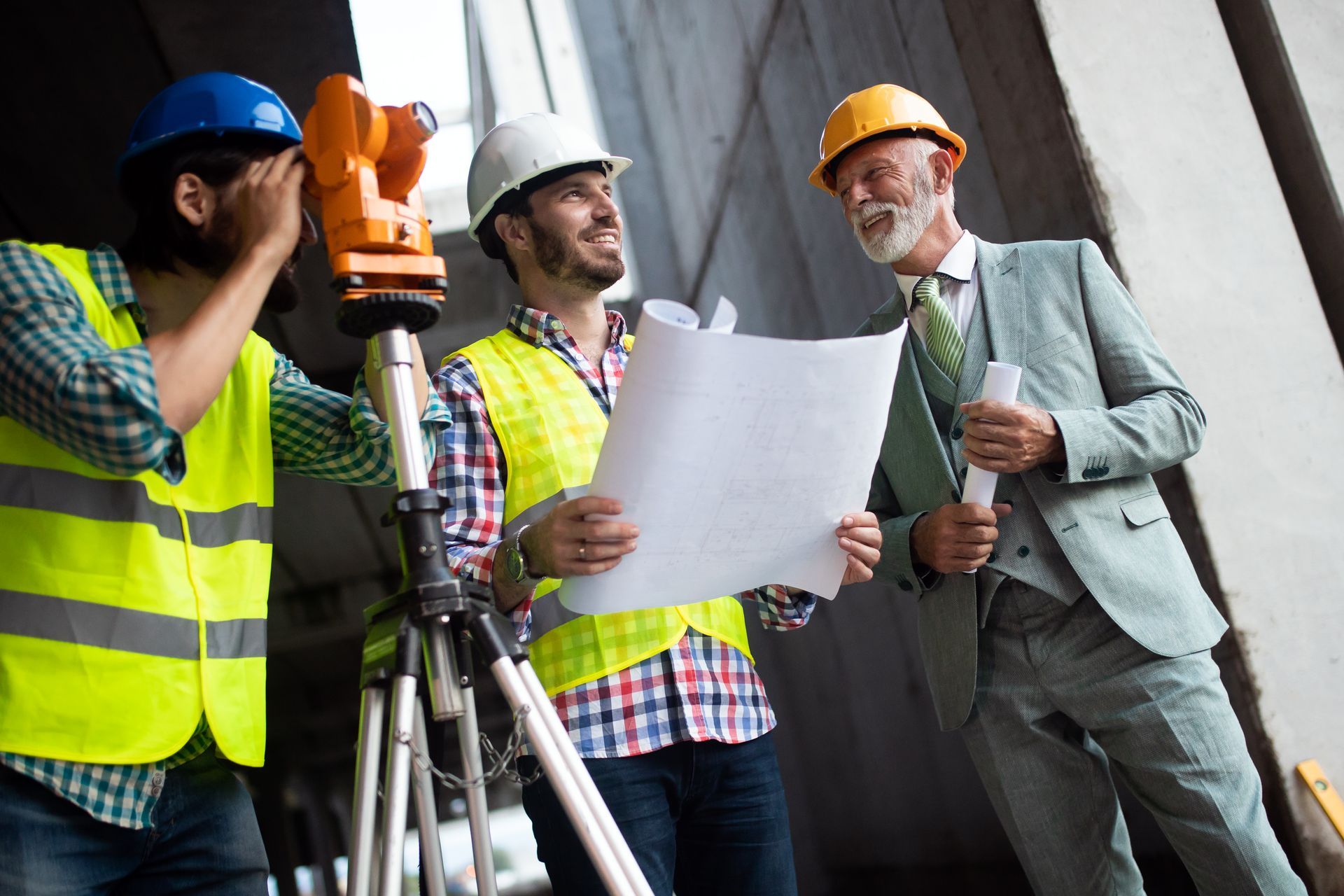 A group of construction workers are looking at a blueprint on a construction site.