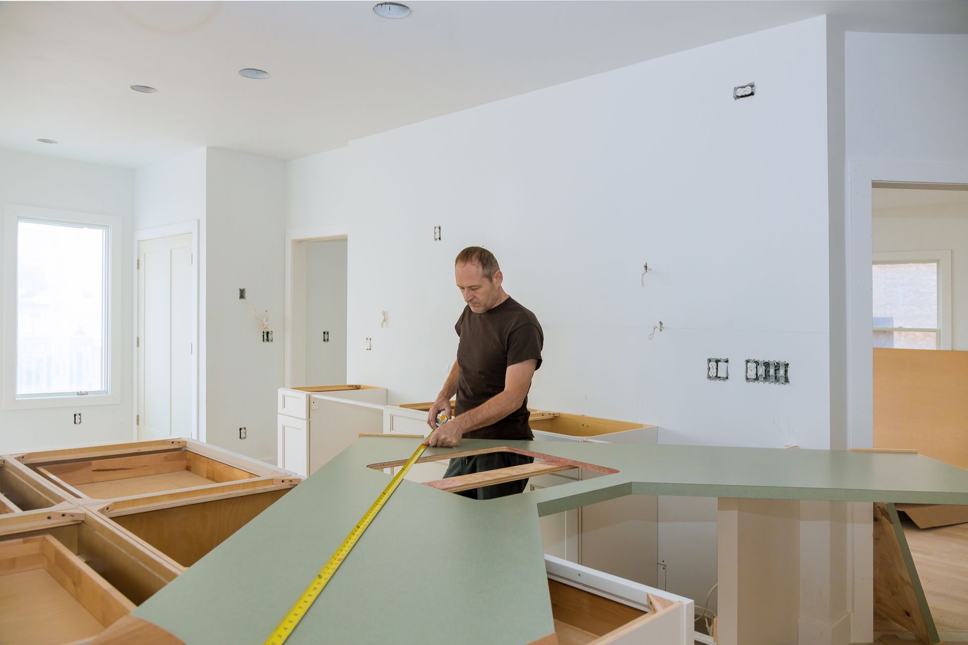 A man is measuring a counter top with a tape measure.