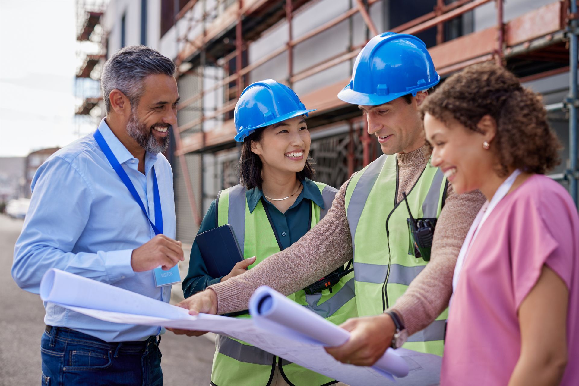 A group of construction workers are looking at blueprints on a construction site.