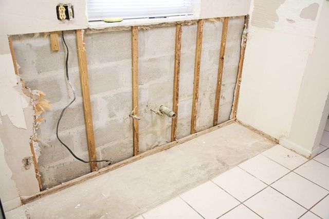 A bathroom with tile floors and a brick wall with wooden beams.