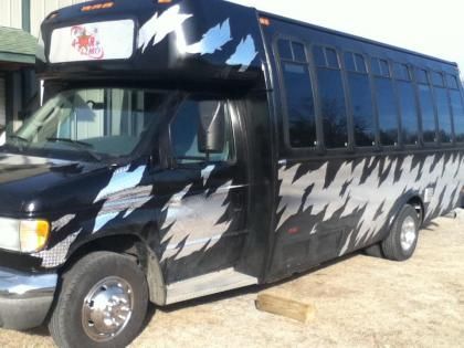 Black custom-painted van parked outdoors on dirt, with white lightning-like graphics along the side.