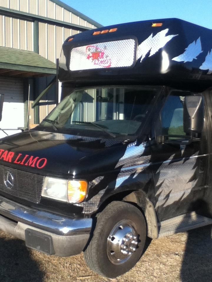 Black limousine-style van parked beside a building, with red STAR LIMO lettering on the hood.