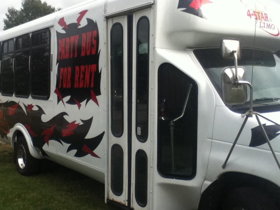 White shuttle bus with black-red graphics and text parked on grass, front side view