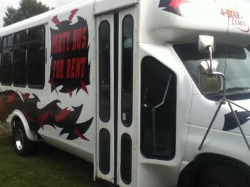 White shuttle bus with black and red flame graphics and tinted windows parked outdoors