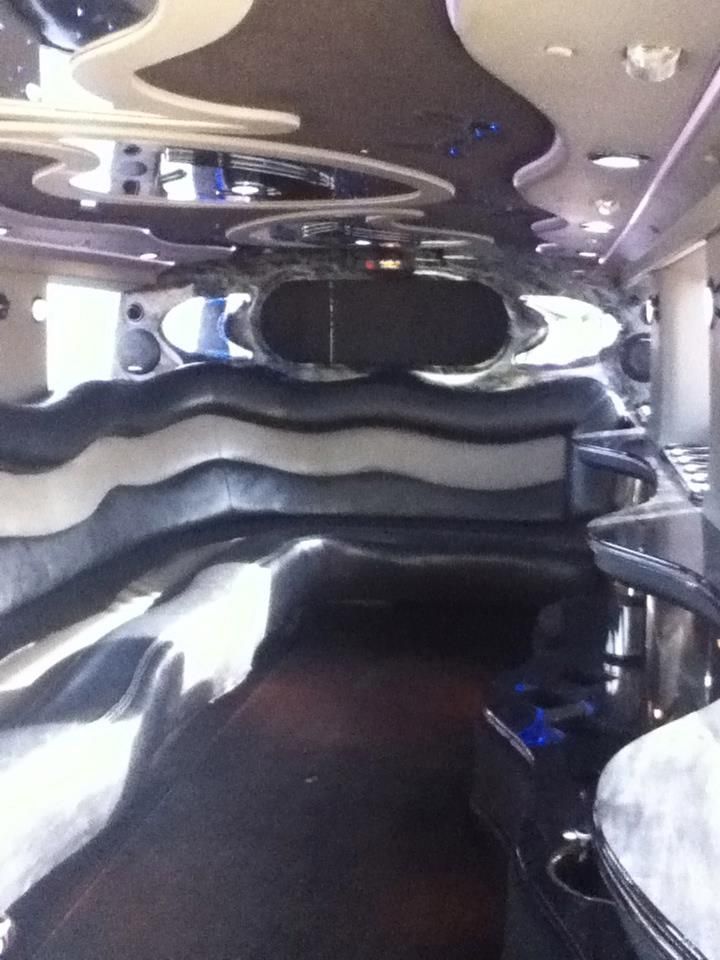Mirrored lounge interior with wavy metallic walls, ceiling lights, and a dark bench seating area
